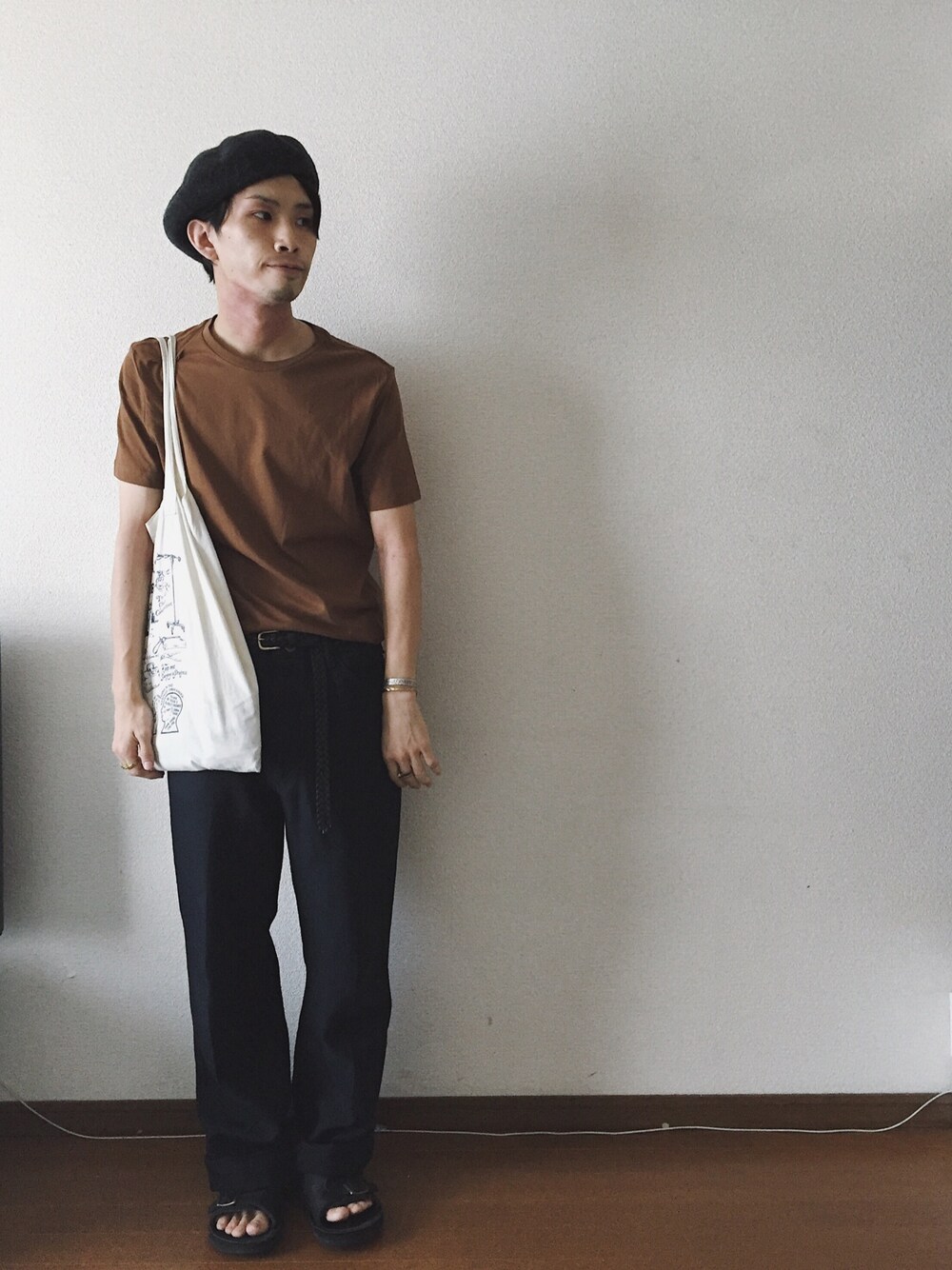 ブラウン系のTシャツ/カットソー、ブラック系のサンダル、ブルー系のスラックスを着用したメンズの夏コーディネートの1枚目の写真