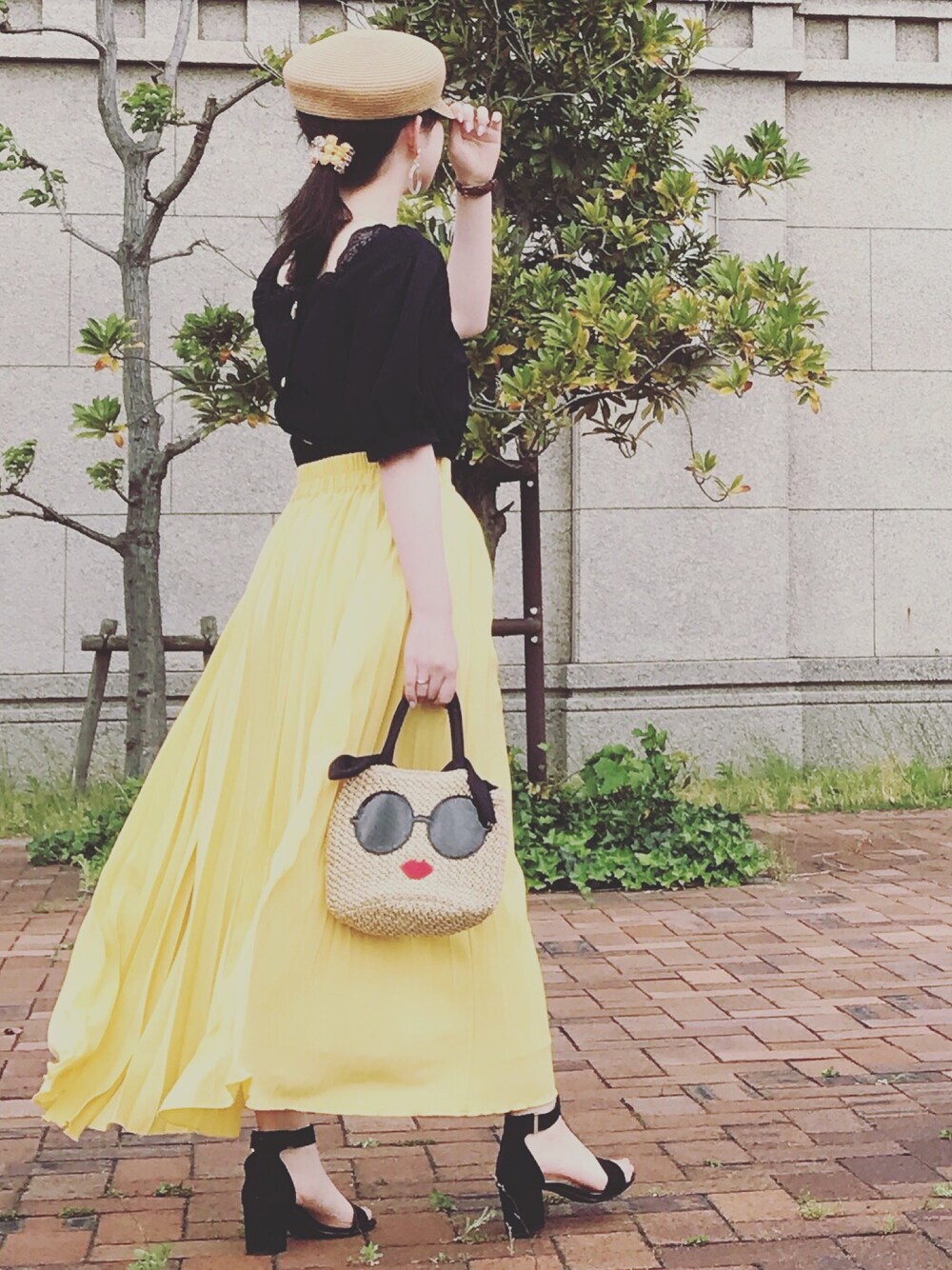 イエロー系のスカート、ブラック系のサンダル、ブラウン系のキャスケットを着用したレディースの春コーディネートの1枚目の写真