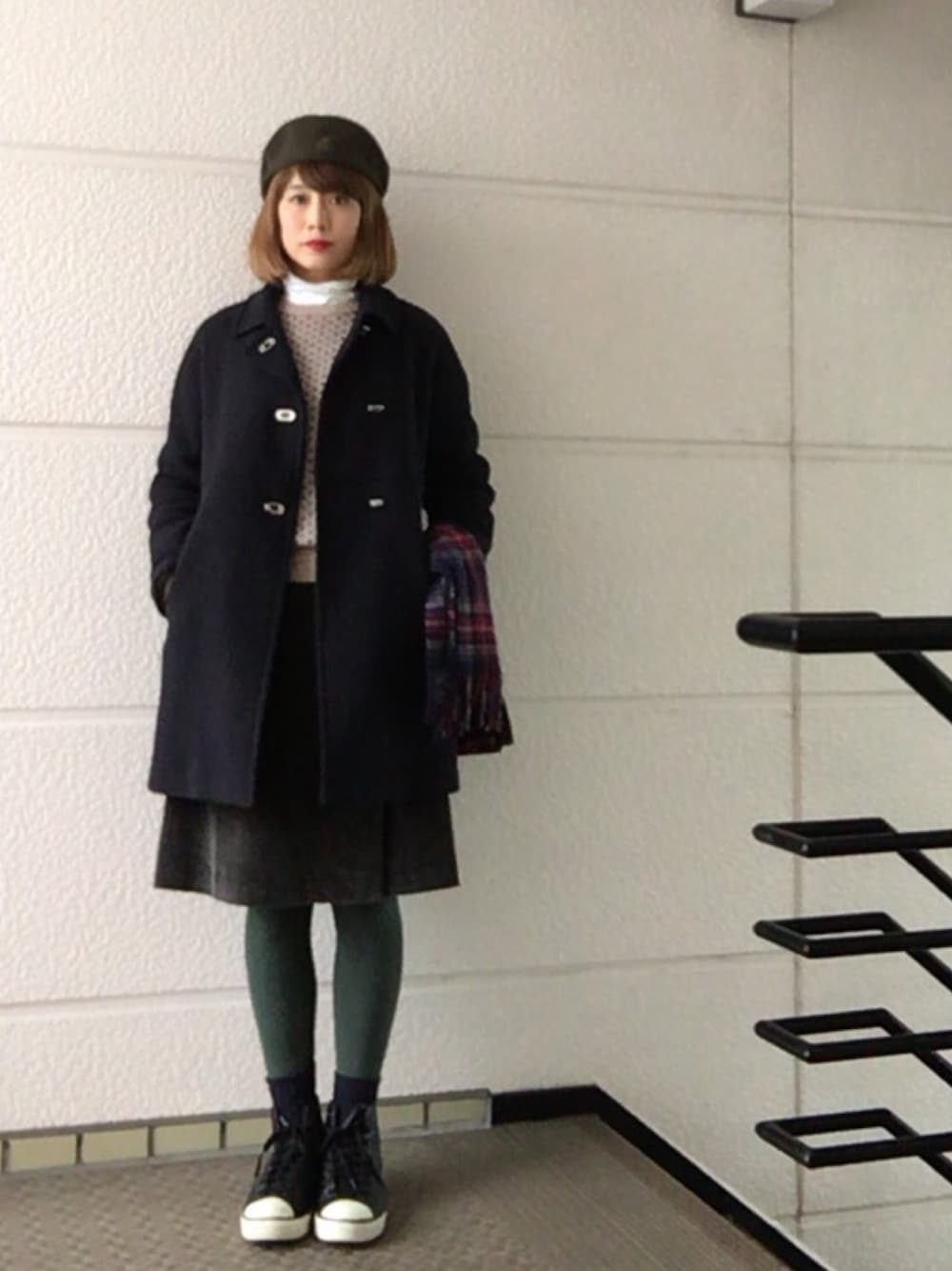 ブルー系のステンカラーコート、ベージュ系のニット/セーター、ブラック系のスニーカーを着用したレディースの冬コーディネートの1枚目の写真