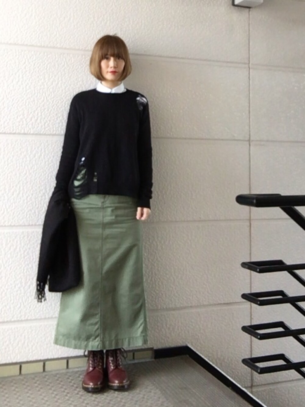 ブラック系のニット/セーター、グリーン系のスカート、レッド系のブーツを着用したレディースの冬コーディネートの1枚目の写真