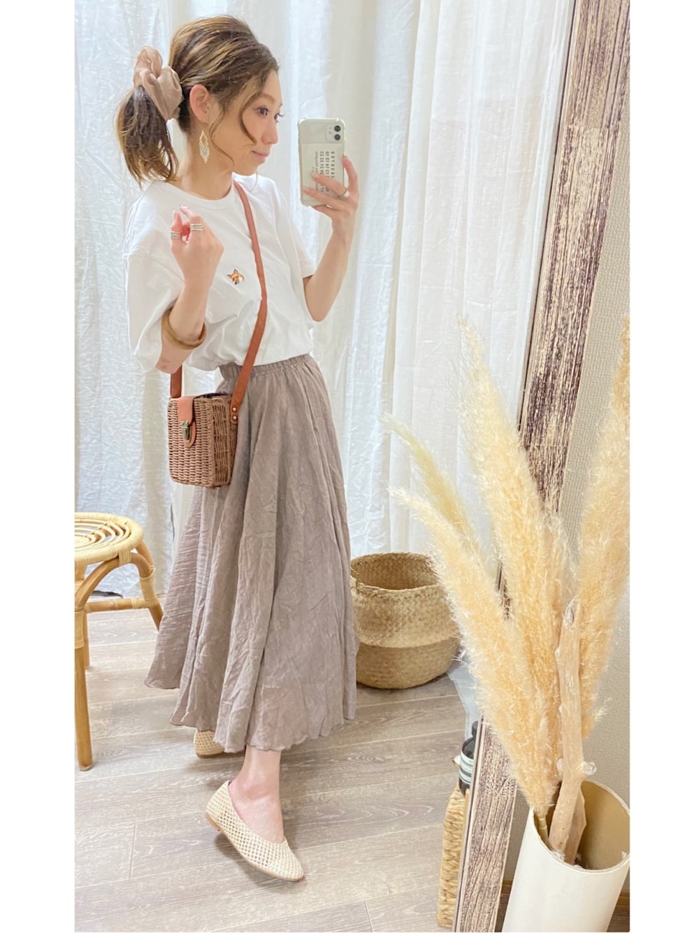 ブラウン系のスカート、ブラウン系のかごバッグ、ホワイト系のTシャツ/カットソーを着用したレディースの春コーディネートの1枚目の写真