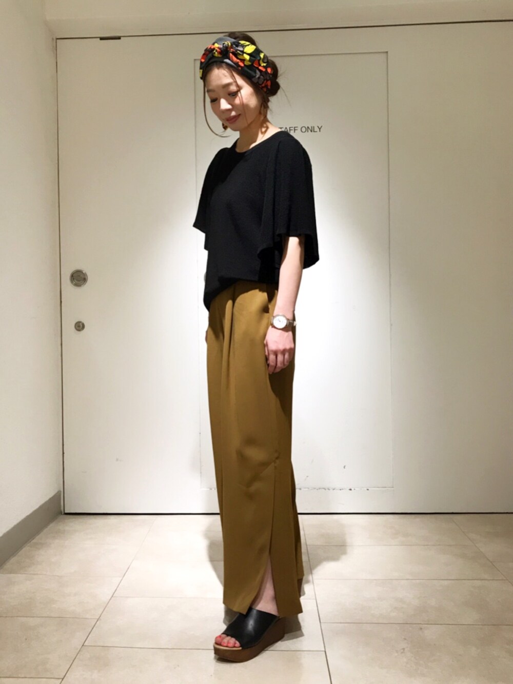 ブラック系のニット/セーター、ベージュ系のその他パンツ、ブラック系のサンダルを着用したレディースの春コーディネートの1枚目の写真