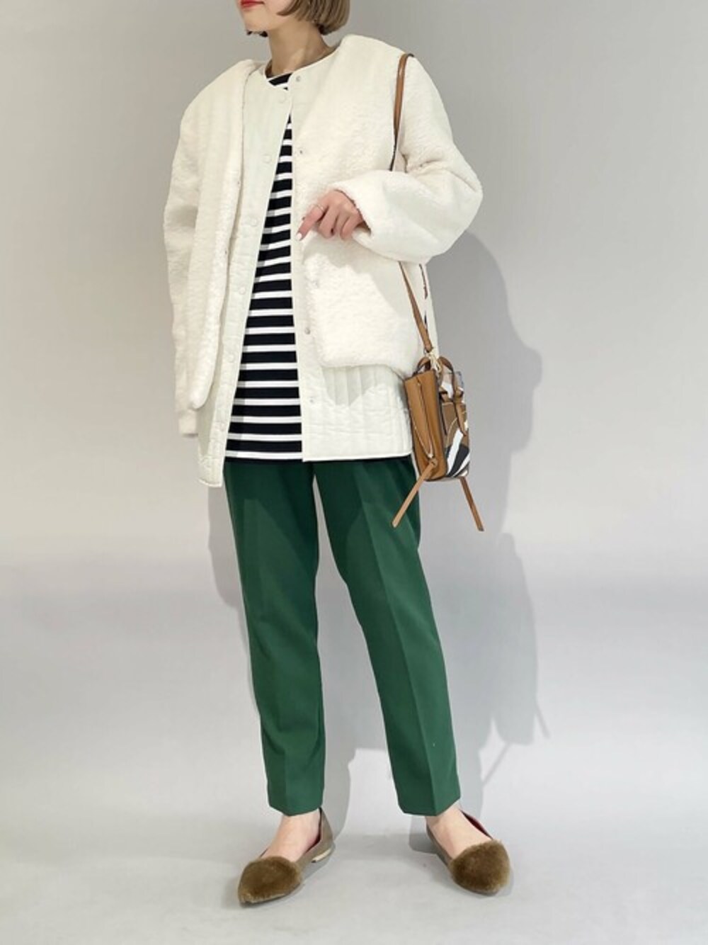 ホワイト系のベスト、ブラック系のTシャツ/カットソー、グリーン系のスラックスを着用したレディースの冬コーディネートの1枚目の写真