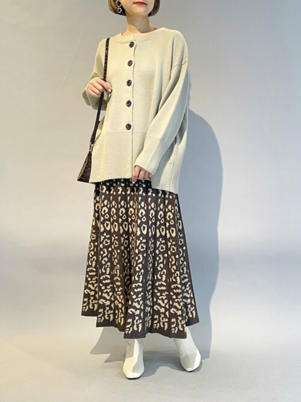 ベージュ系のカーディガン/ボレロ、ブラウン系のスカートを着用したレディースの冬コーディネートの1枚目の写真