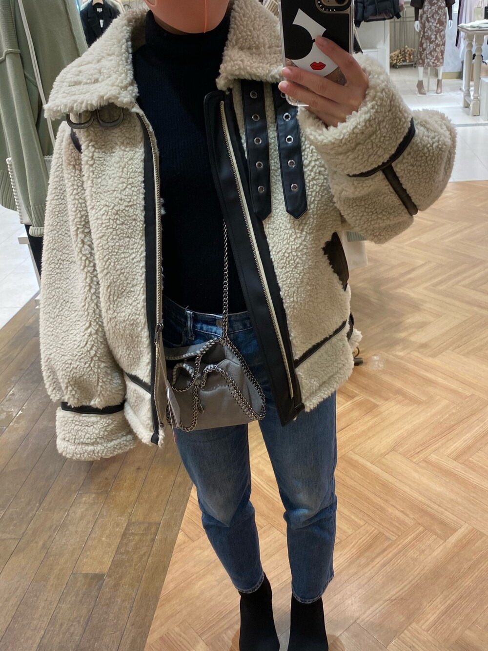 ベージュ系のムートンコート、ブラック系のニット/セーター、ブルー系のデニムパンツを着用したレディースの冬コーディネートの1枚目の写真