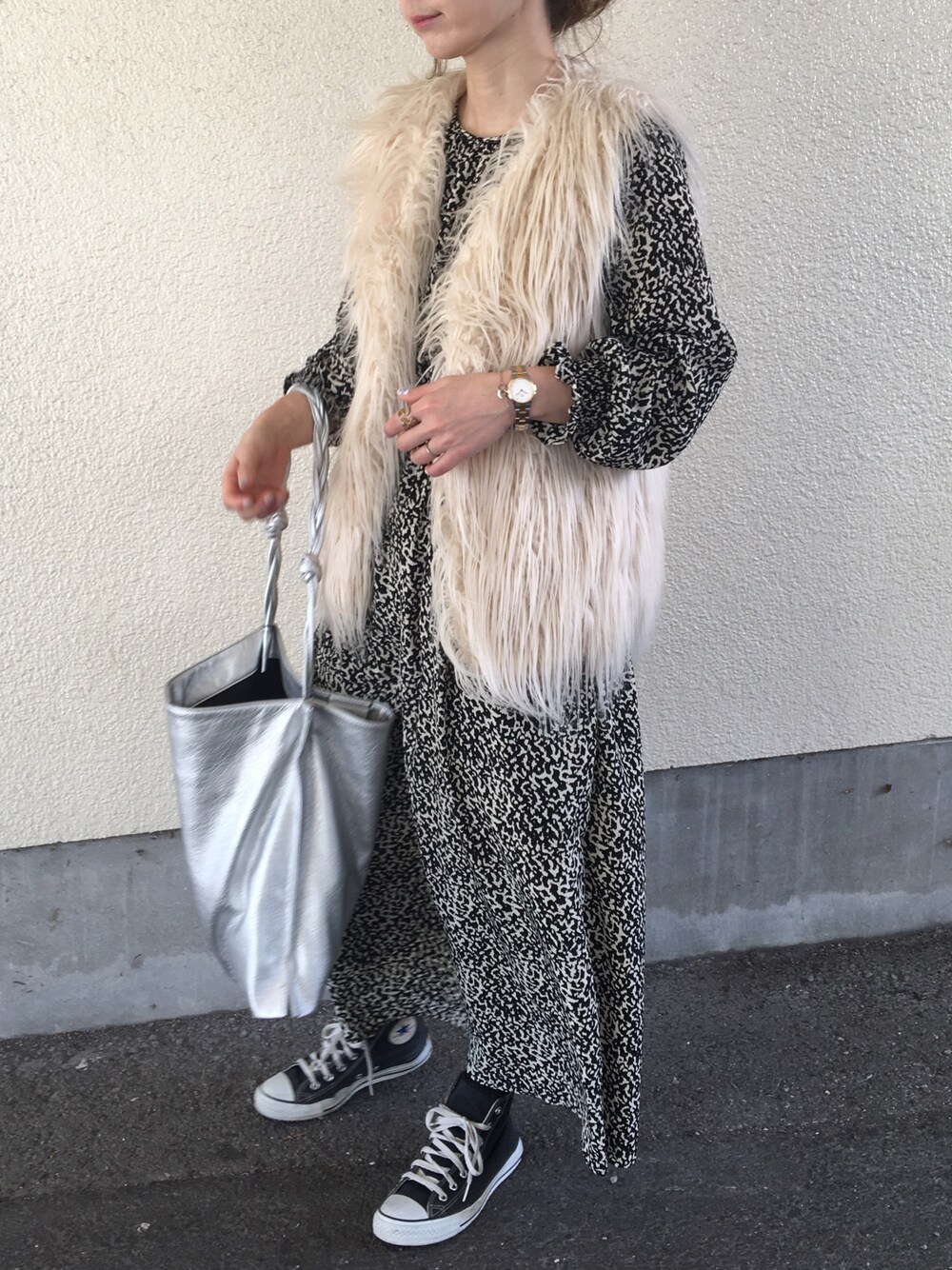 ブラック系のワンピース、ホワイト系のベスト、ゴールド系の腕時計を着用したレディースの冬コーディネートの1枚目の写真