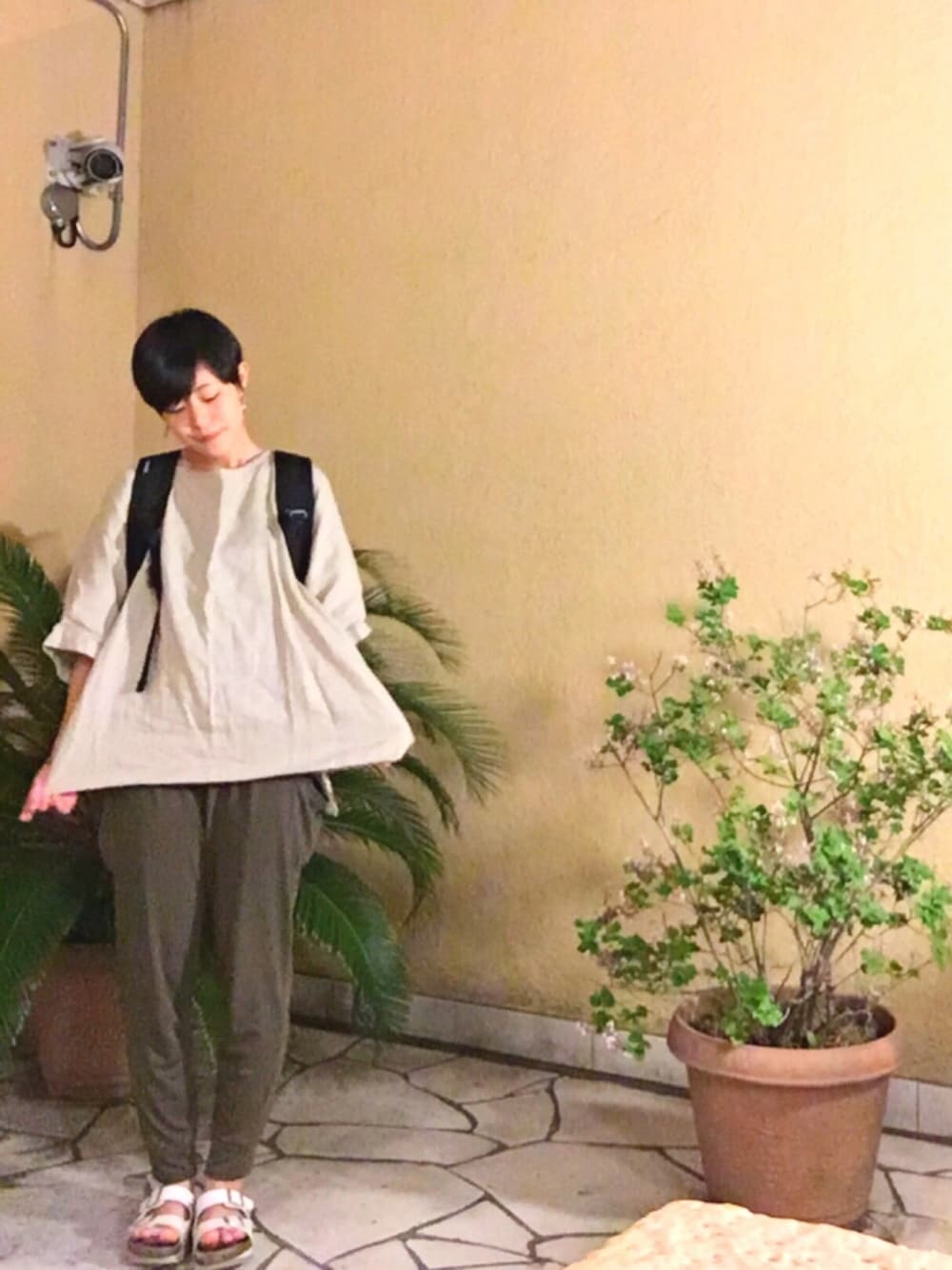 ブラック系のバックパック/リュック、ベージュ系のチュニック、ホワイト系のサンダルを着用したレディースの春コーディネートの1枚目の写真