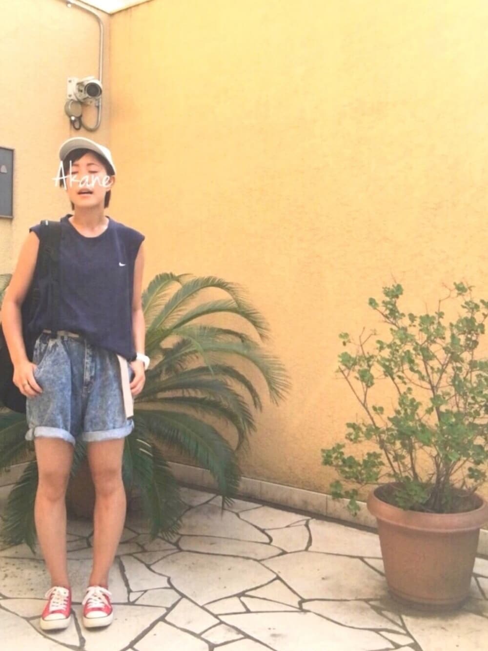 ブルー系のタンクトップ、ブラック系のバックパック/リュック、ブルー系のデニムパンツを着用したレディースの夏コーディネートの1枚目の写真