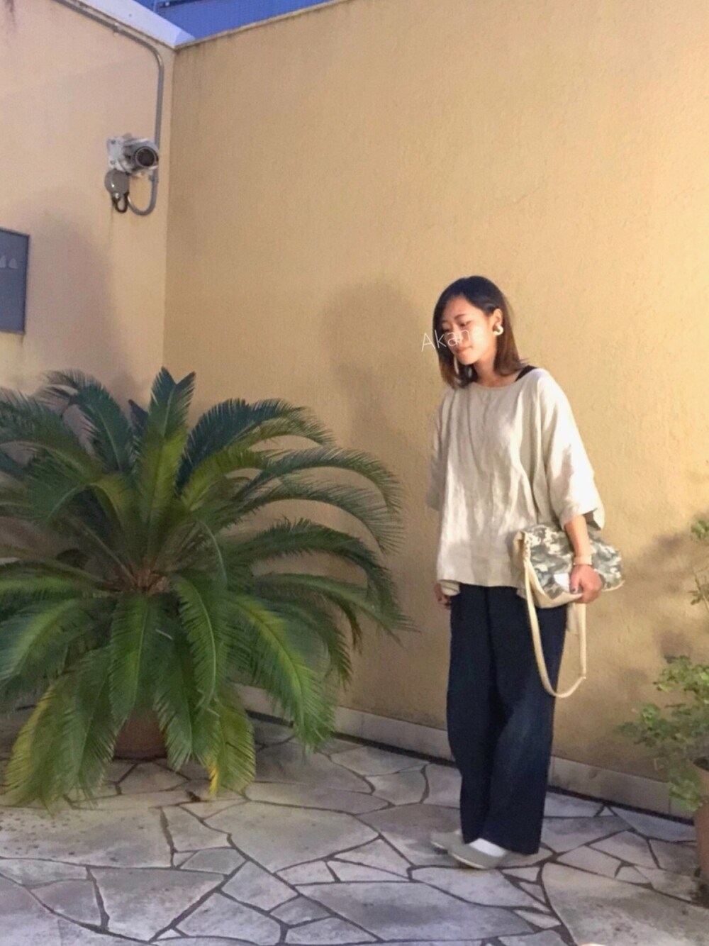 ベージュ系のチュニック、グリーン系のクラッチバッグ、ブルー系のパンツを着用したレディースの秋コーディネートの1枚目の写真