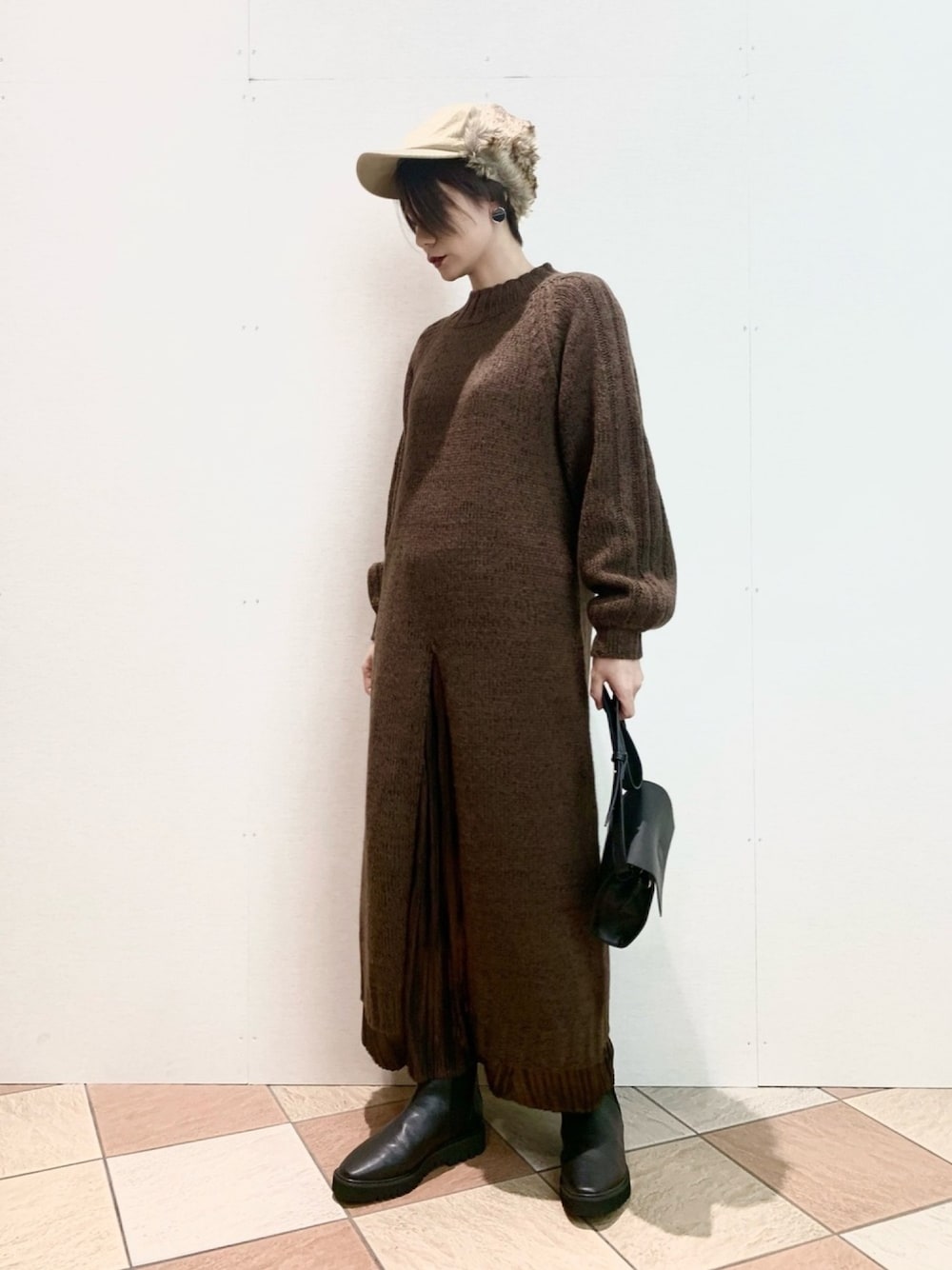 ブラウン系のワンピース、ブラウン系のスカート、ブラック系のショルダーバッグを着用したレディースの冬コーディネートの1枚目の写真