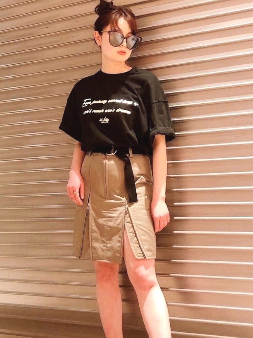 ブラック系のTシャツ/カットソー、グリーン系のスカート、ブラック系のサングラスを着用したレディースの春コーディネートの1枚目の写真