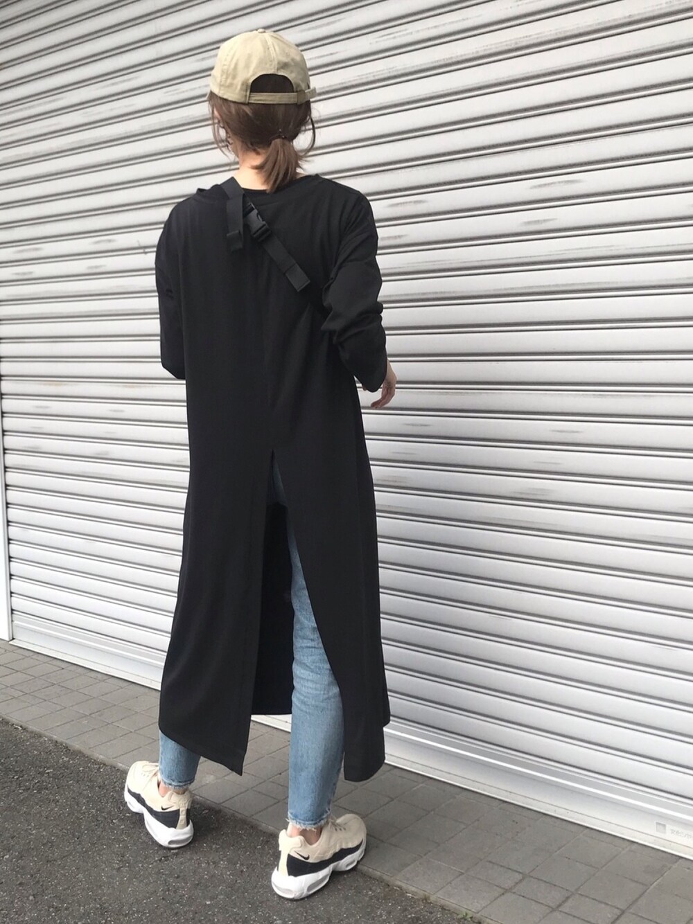 ブラック系のワンピース/ドレス、ブラック系のスニーカー、ブルー系のデニムパンツを着用したレディースの春コーディネートの1枚目の写真