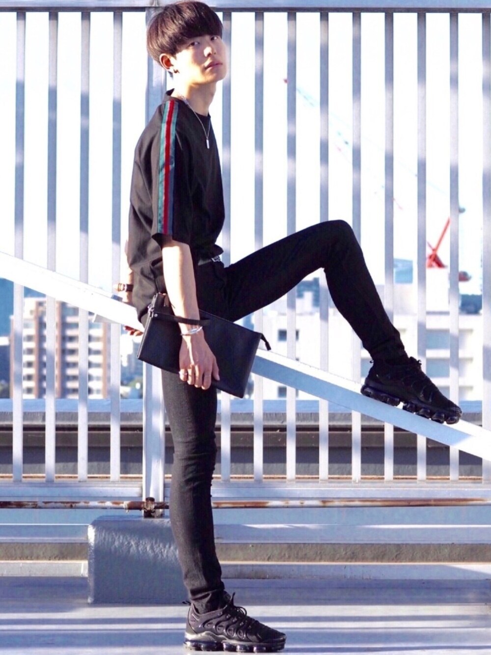 ブラック系のTシャツ/カットソー、ブラック系のクラッチバッグ、ブラック系のスニーカーを着用したメンズの夏コーディネートの1枚目の写真