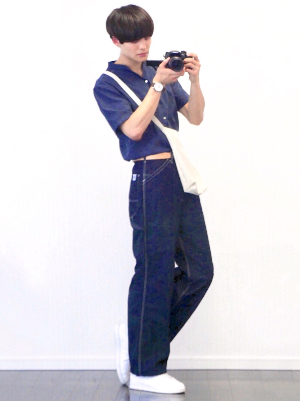 ブルー系のデニムパンツ、ホワイト系のスニーカー、ホワイト系のショルダーバッグを着用したメンズの夏コーディネートの1枚目の写真