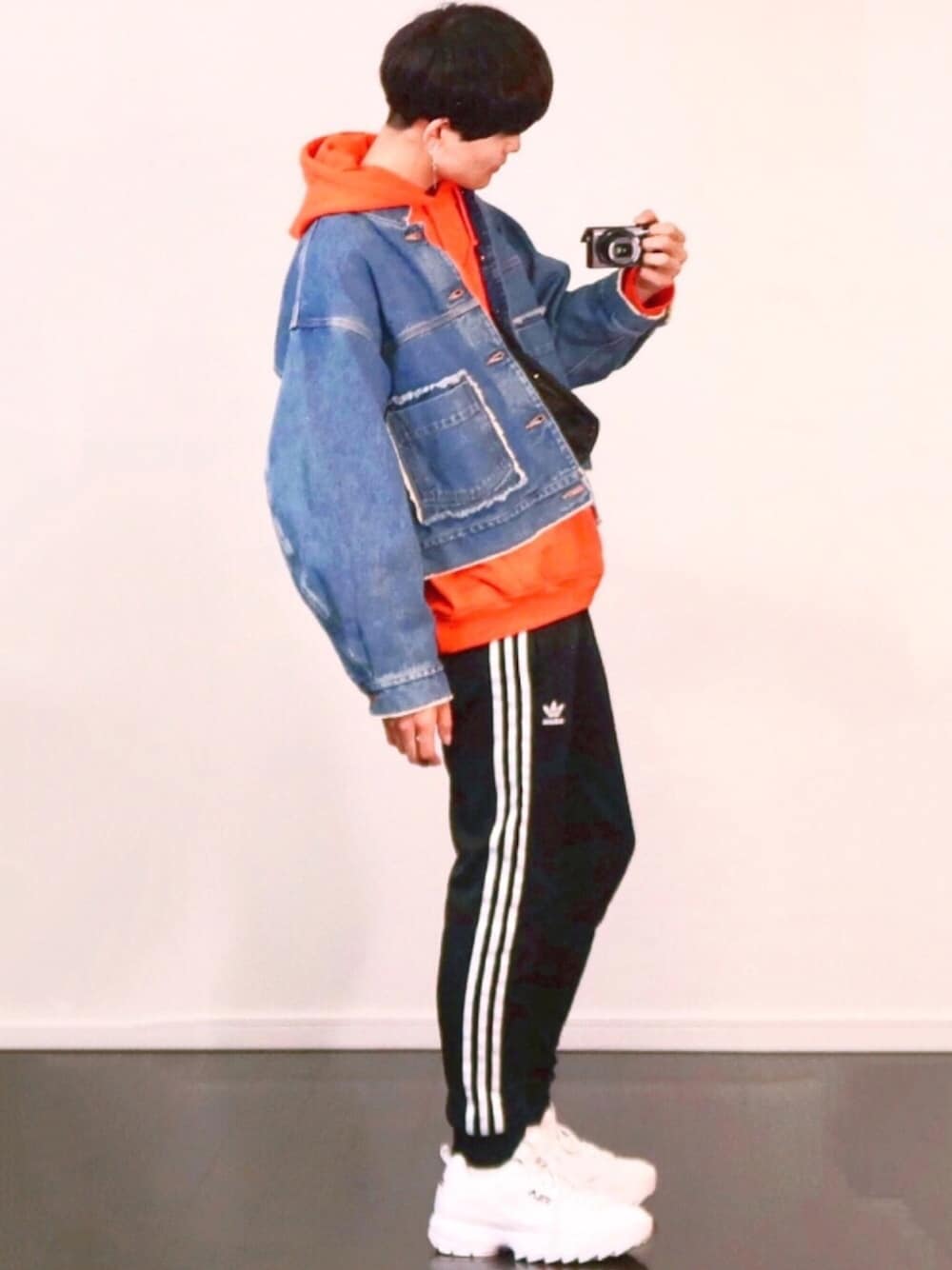 ブラック系のその他パンツ、ホワイト系のスニーカー、オレンジ系のパーカーを着用したメンズの秋コーディネートの1枚目の写真