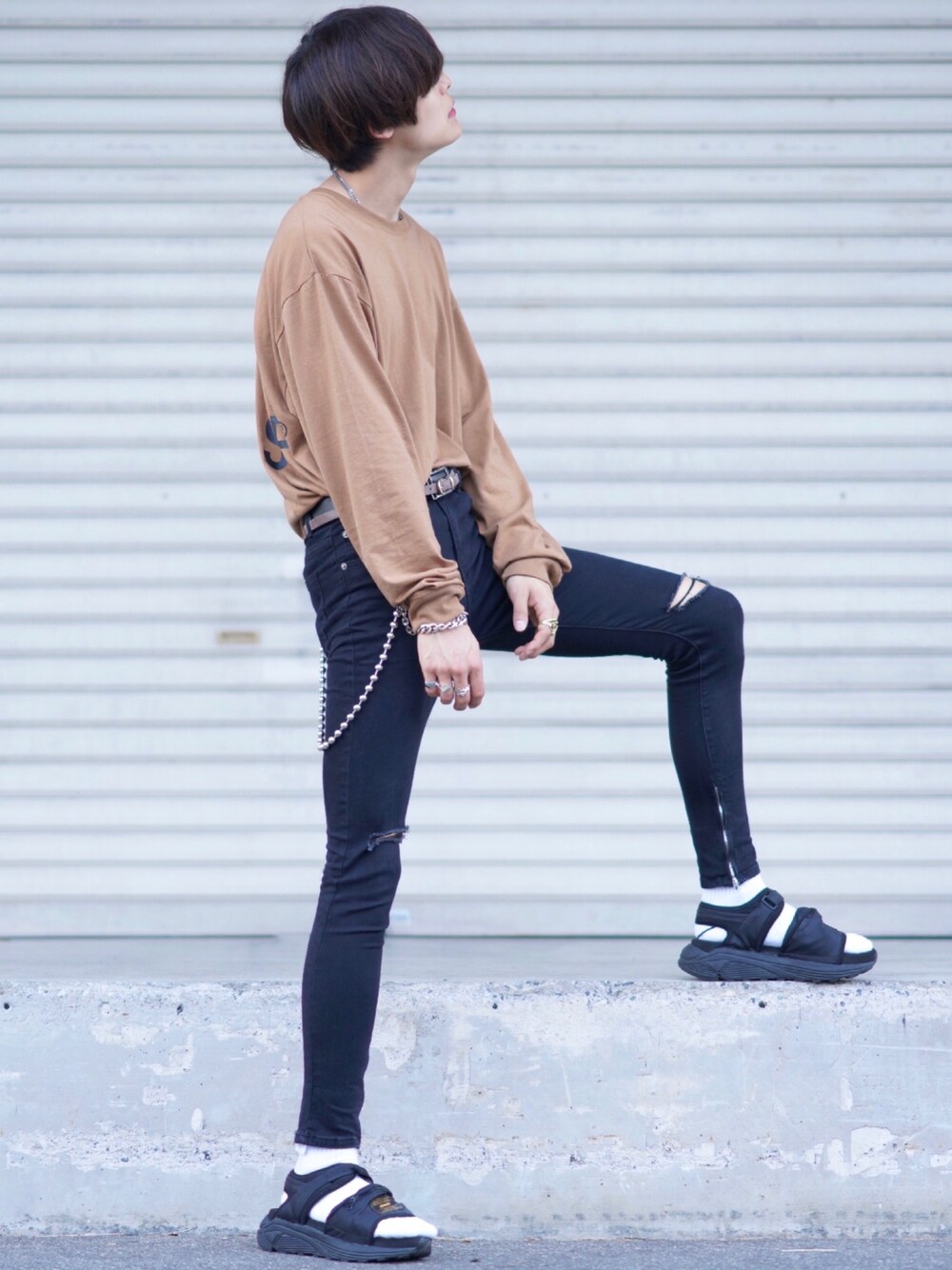 ブラック系のデニムパンツ、ブラック系のサンダル、ベージュ系のTシャツ/カットソーを着用したメンズの夏コーディネートの1枚目の写真