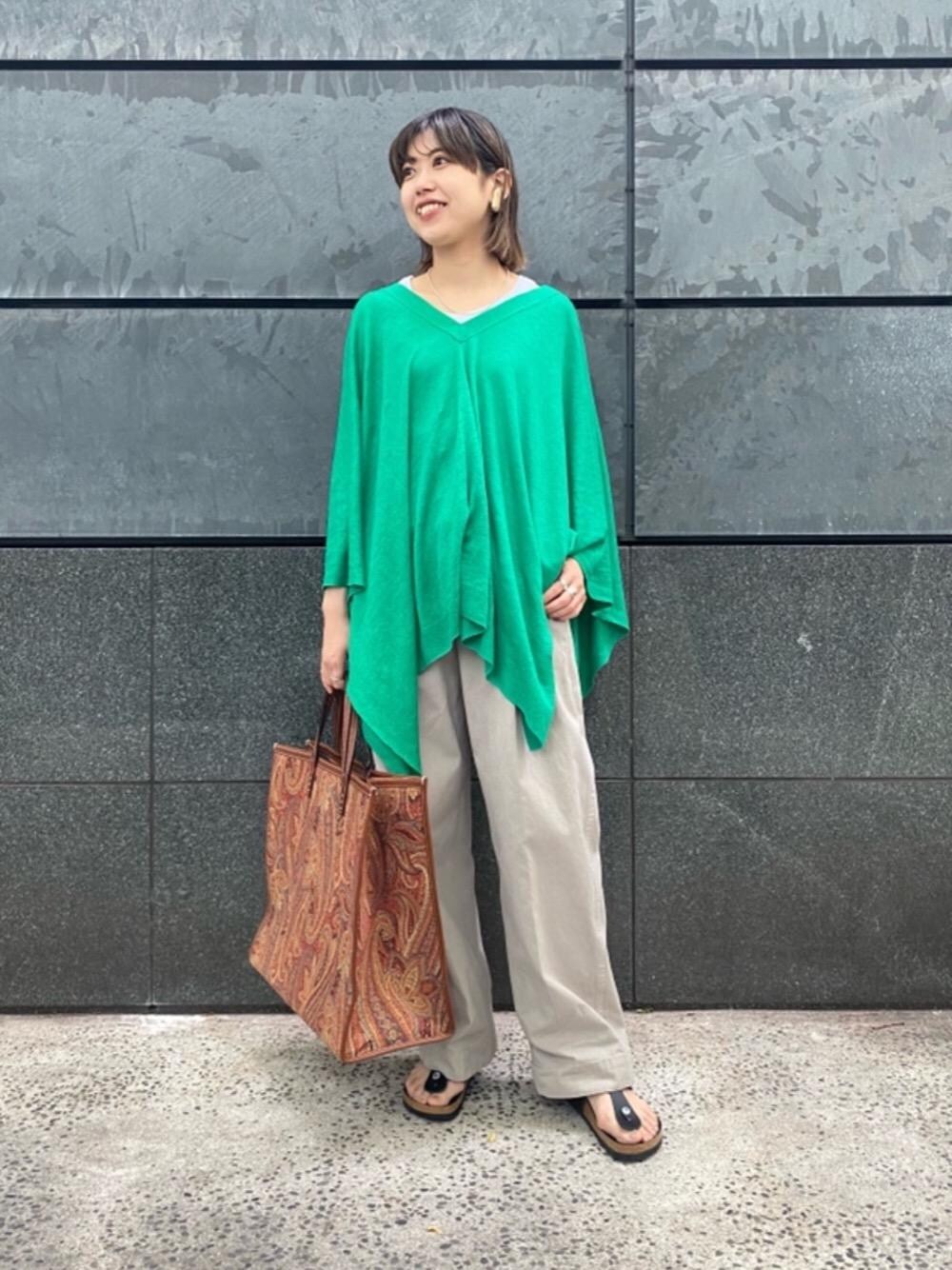 オレンジ系のトートバッグ、グリーン系のカーディガン/ボレロ、ブラック系のサンダルを着用したレディースの春コーディネートの1枚目の写真