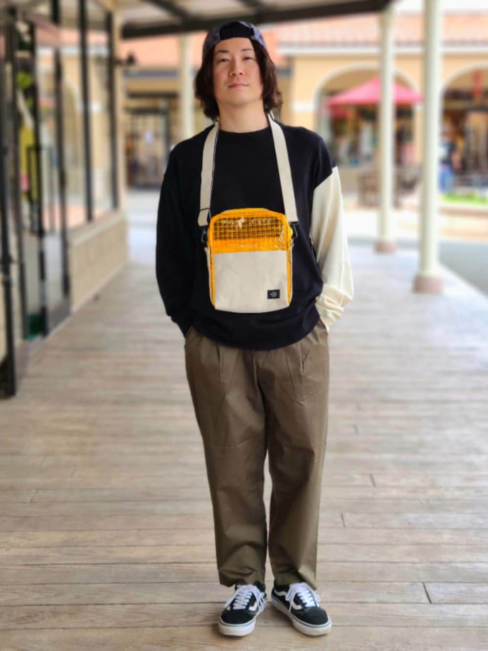 ブラック系のスニーカー、グリーン系のその他パンツ、オレンジ系のショルダーバッグを着用したメンズの夏コーディネートの1枚目の写真