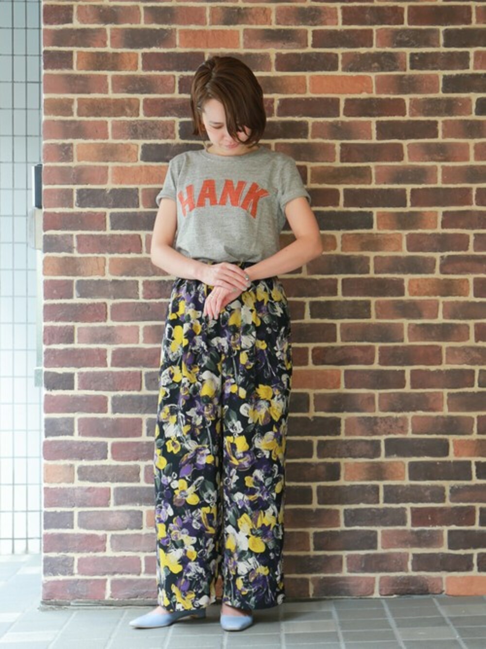 「ロゴT、柄パンツ、Tシャツ、フラットシューズ、ワイドパンツ、ラフスタイル、カジュアルコーデ、ラクチンコーデ、オトナカジュアル」｜「NOMBRE IMPAIRのペイントフラワープリント　ワイドパンツ（その他パンツ、パープル系）」を使った、RolladeX STAFFさん（レディース・160cm）の春コーディネートの1枚目の写真