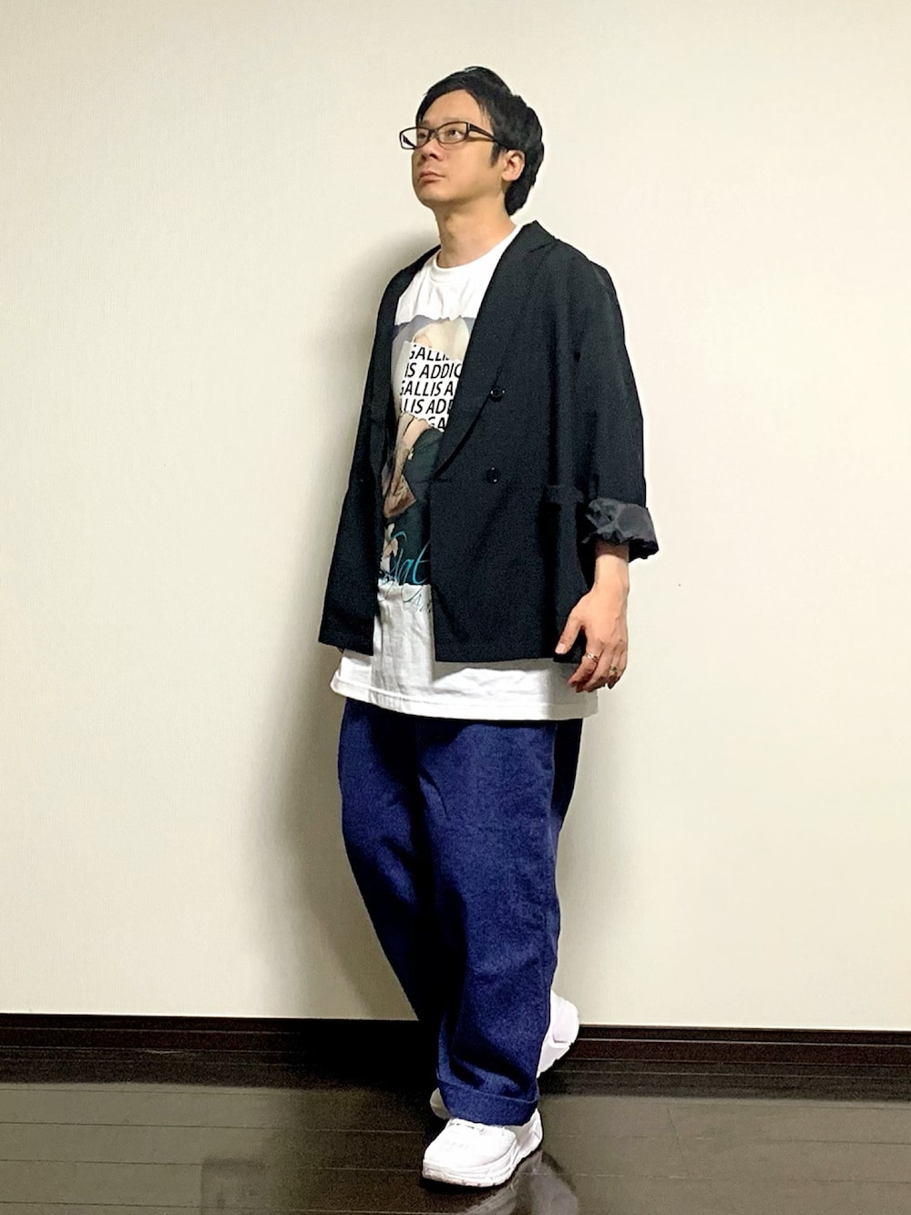 ブラック系のテーラードジャケット、ホワイト系のTシャツ/カットソー、ブルー系のデニムパンツを着用したメンズの春コーディネートの1枚目の写真