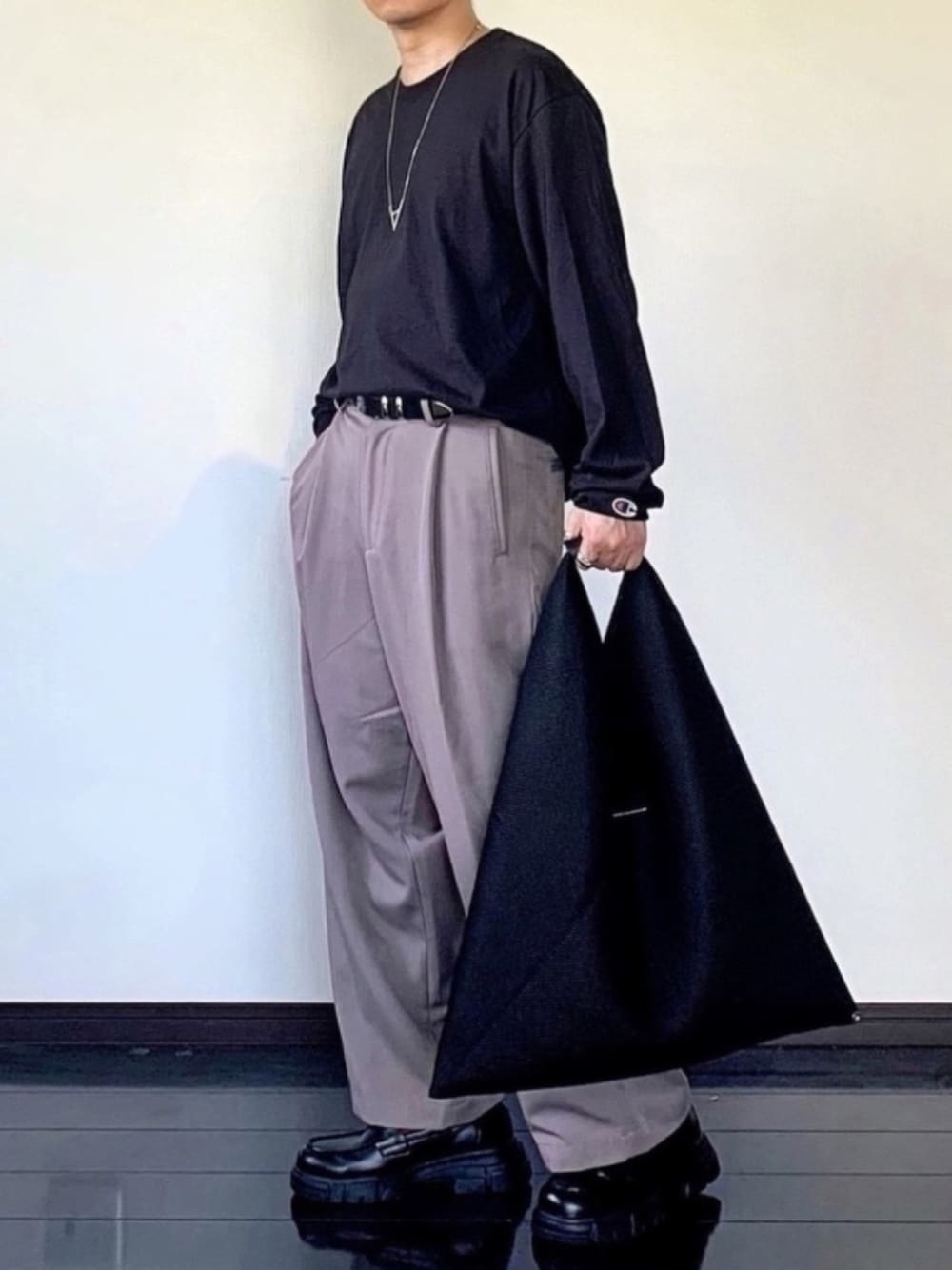 ブラック系のTシャツ/カットソー、ベージュ系のスラックス、ブラック系のローファーを着用したメンズの夏コーディネートの1枚目の写真