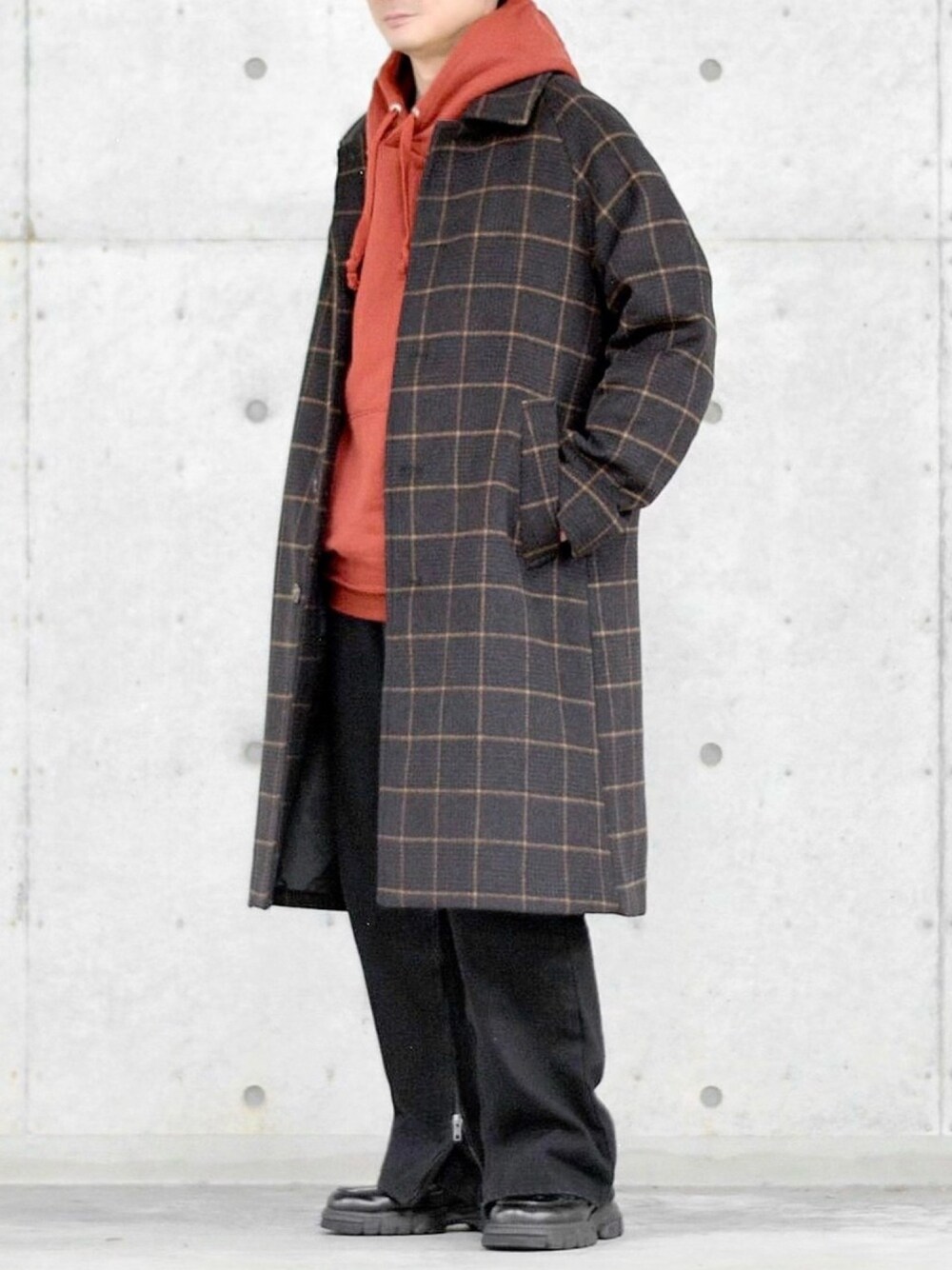 ブラウン系のステンカラーコート、ブラウン系のパーカー、ブラック系のデニムパンツを着用したメンズの冬コーディネートの1枚目の写真