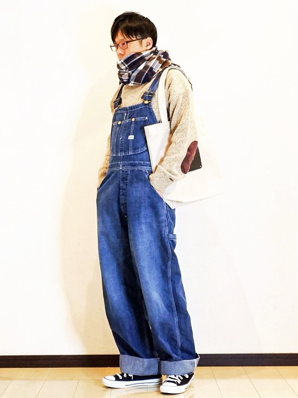 ベージュ系のニット/セーター、ブルー系のサロペット/オーバーオール、ブラック系のスニーカーを着用したメンズの冬コーディネートの1枚目の写真