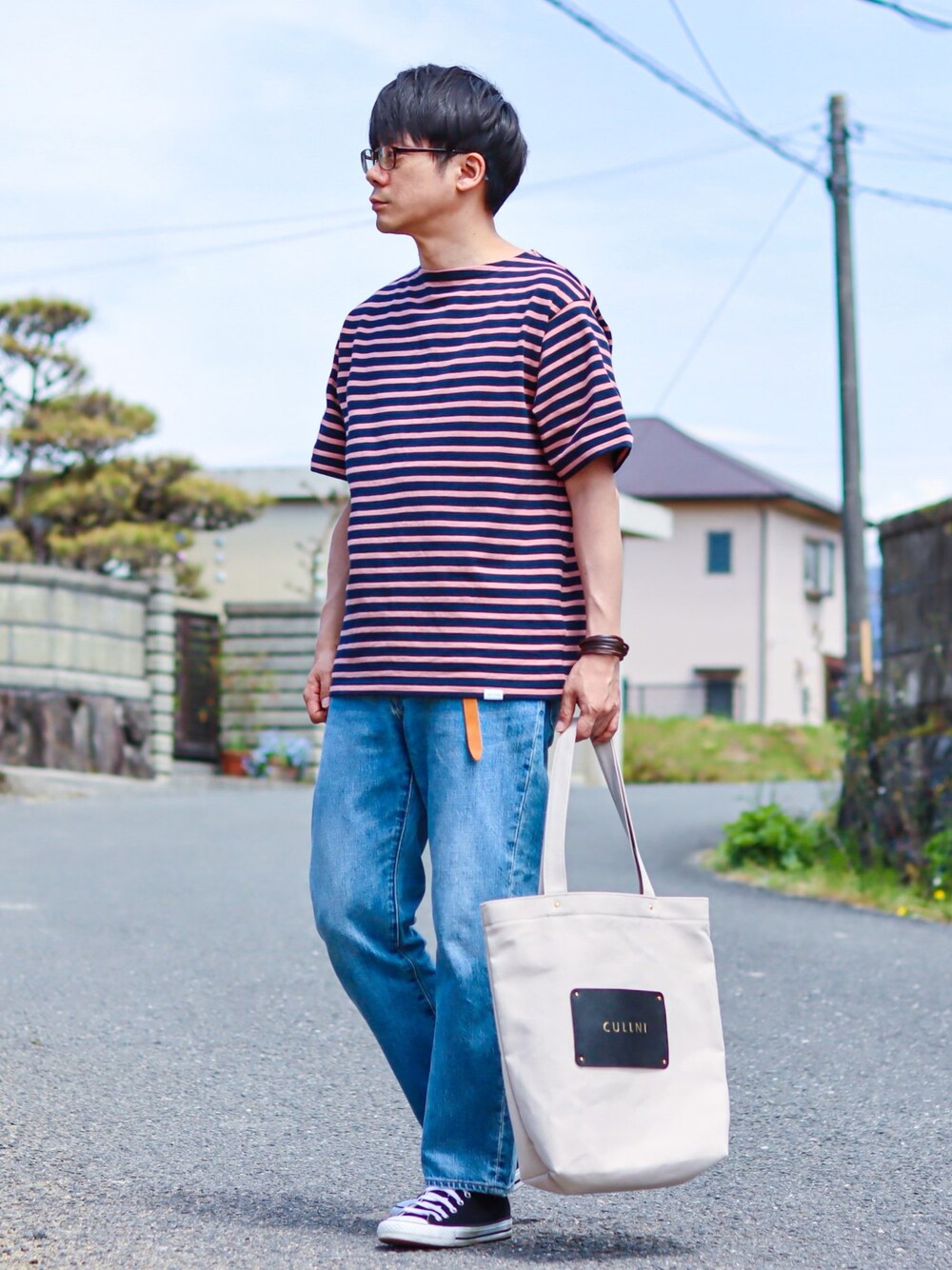 ピンク系のTシャツ/カットソー、ブルー系のデニムパンツ、ブラック系のスニーカーを着用したメンズの春コーディネートの1枚目の写真