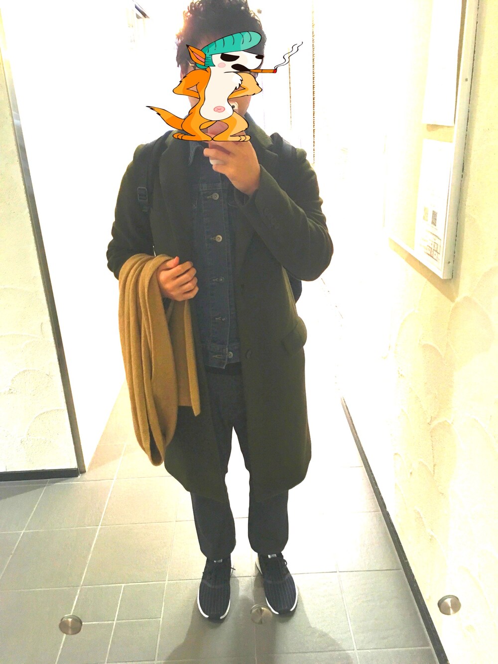 グリーン系のチェスターコート、ブルー系のデニムジャケット、ブラック系のニット/セーターを着用したメンズの冬コーディネートの1枚目の写真