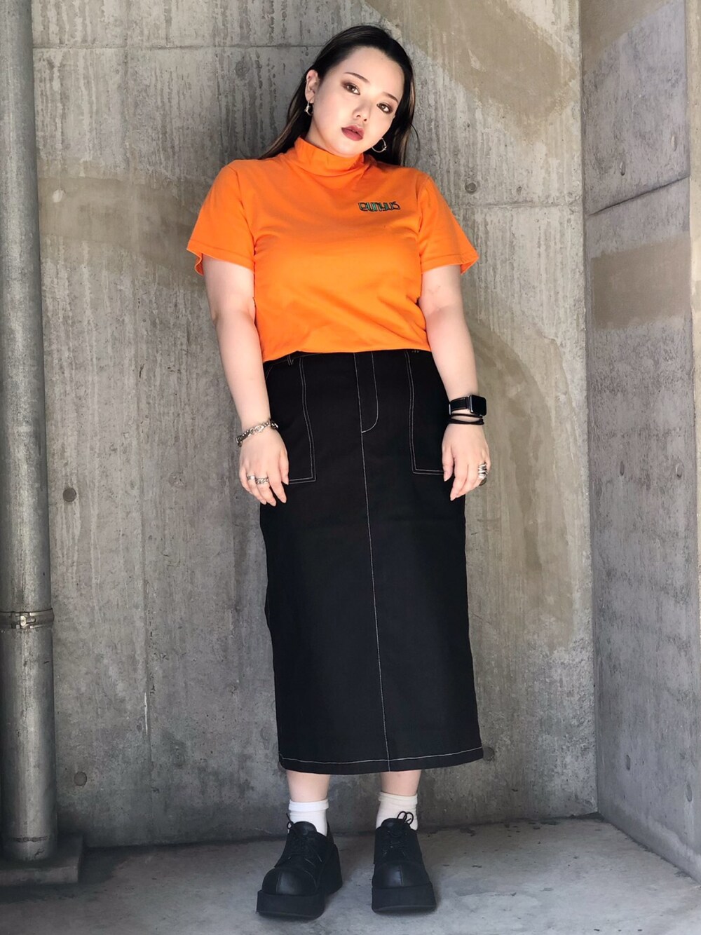 オレンジ系のTシャツ/カットソー、ブラック系のスカートを着用したレディースの夏コーディネートの1枚目の写真