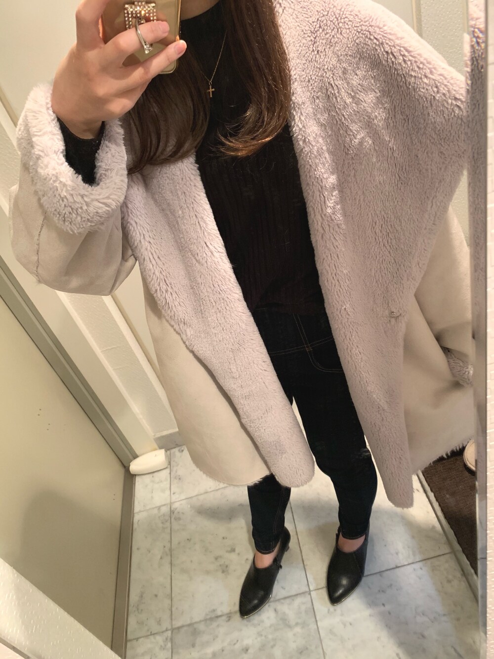 ホワイト系のムートンコート、ブルー系のデニムパンツ、ブラック系のブーティを着用したレディースの秋コーディネートの1枚目の写真
