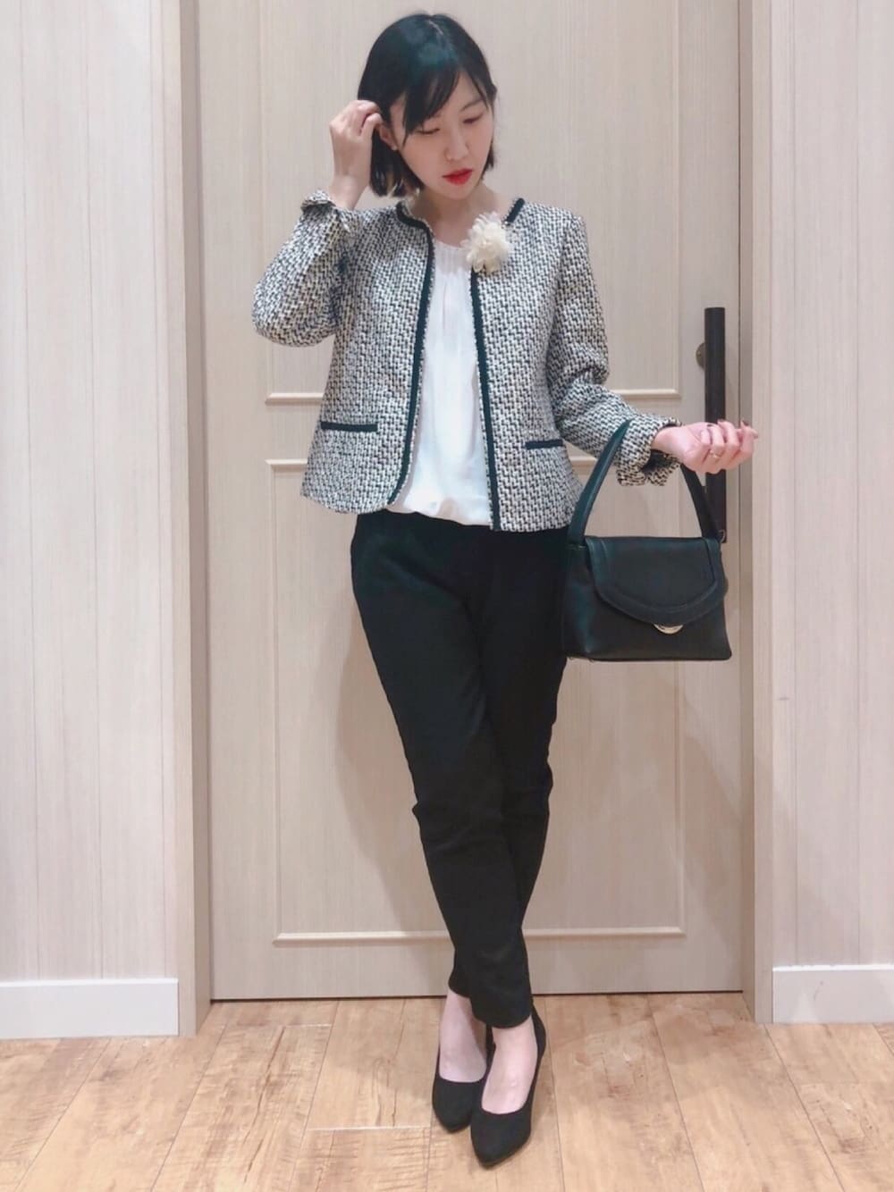 グレー系のノーカラージャケット、ホワイト系のシャツ/ブラウス、ブラック系のハンドバッグを着用したレディースの冬コーディネートの1枚目の写真