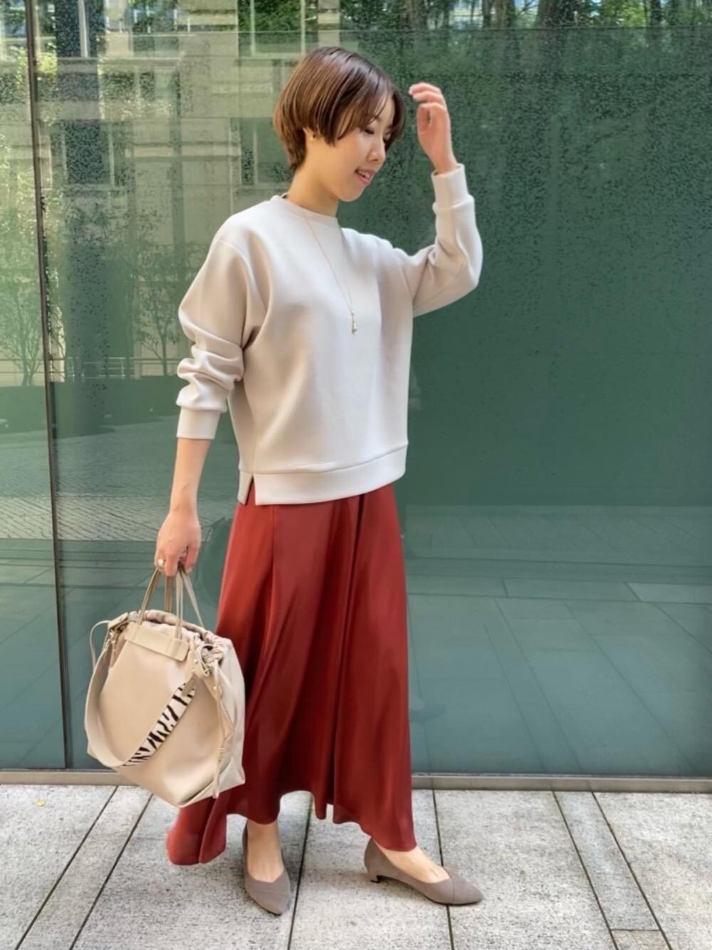 ベージュ系のパンプス、オレンジ系のスカート、ベージュ系のトートバッグを着用したレディースの秋コーディネートの1枚目の写真