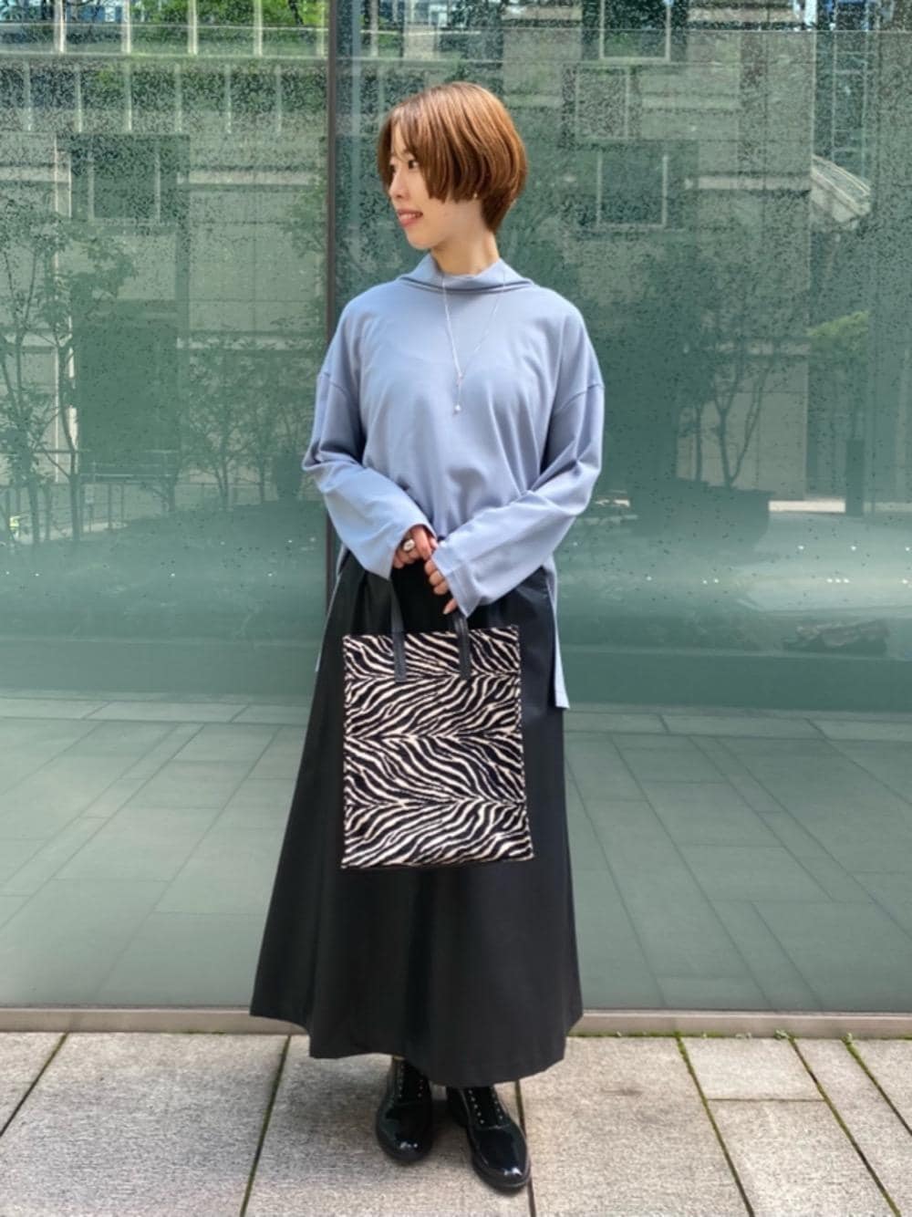 ブラック系のスカート、ブルー系のTシャツ/カットソー、ブラック系のレインシューズを着用したレディースの秋コーディネートの1枚目の写真