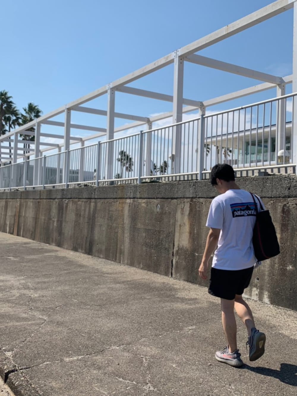 ホワイト系のTシャツ/カットソー、ブラック系のパンツ、グレー系のスニーカーを着用したメンズの夏コーディネートの1枚目の写真