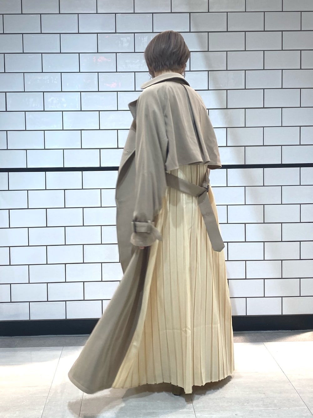 ベージュ系のトレンチコートを着用したレディースの冬コーディネートの1枚目の写真