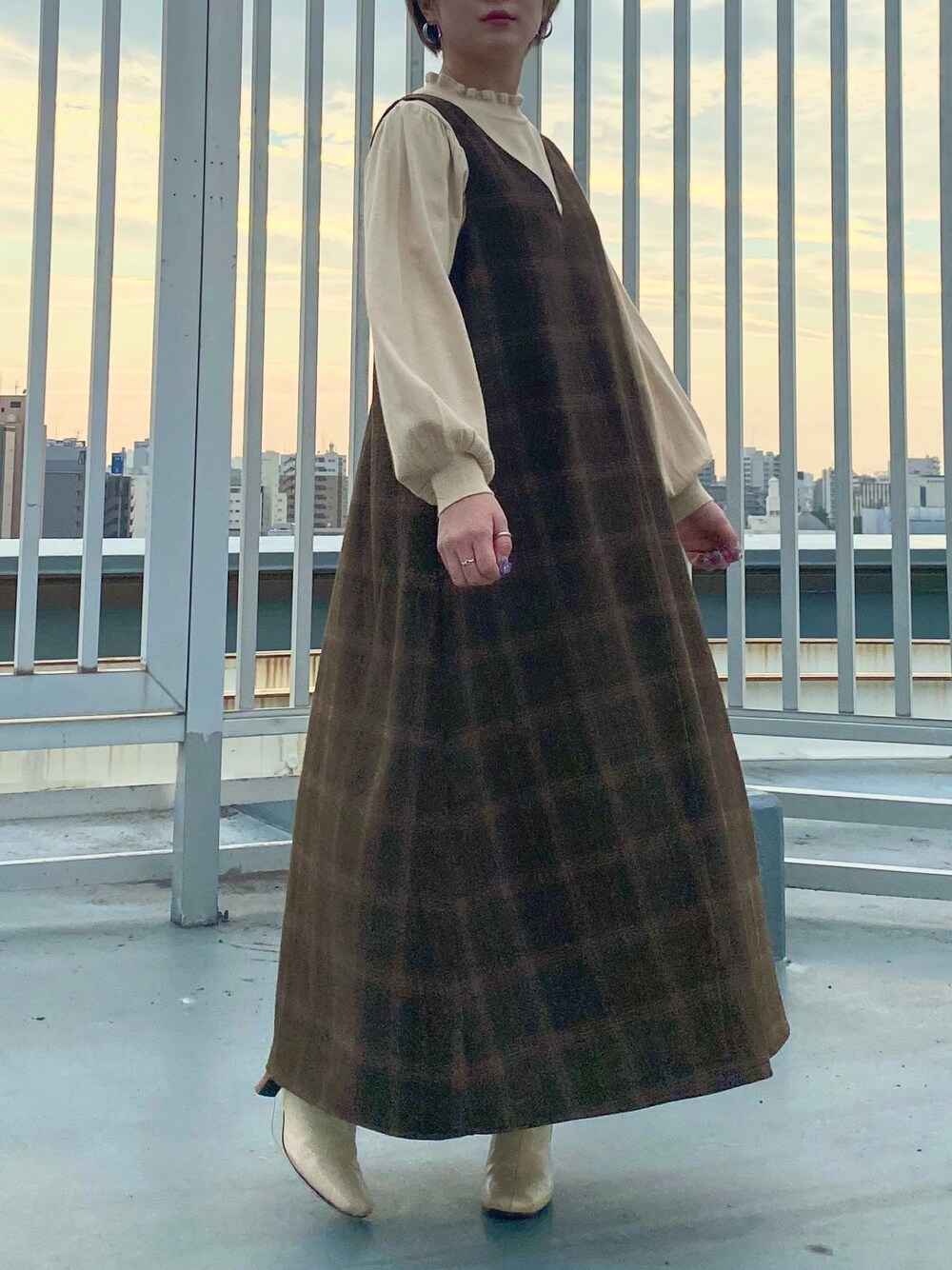 ベージュ系のニット/セーター、ブラウン系のジャンパースカートを着用したレディースの秋コーディネートの1枚目の写真