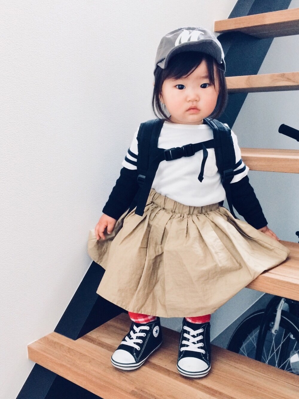 ホワイト系のTシャツ/カットソー、ベージュ系のスカート、ブラック系のスニーカーを着用したキッズの春コーディネートの1枚目の写真