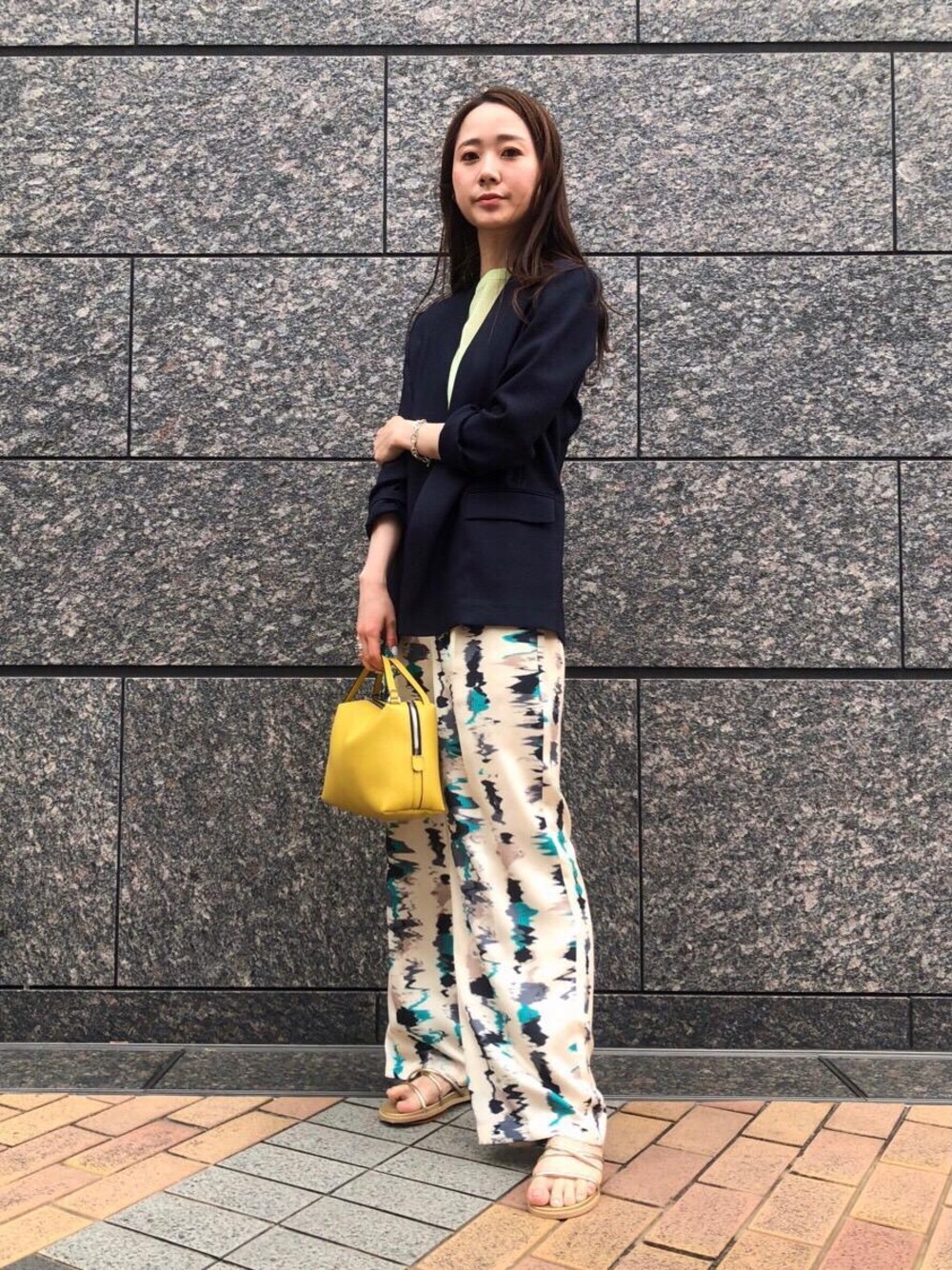 イエロー系のショルダーバッグ、ゴールド系のサンダル、グリーン系のニット/セーターを着用したレディースの春コーディネートの1枚目の写真