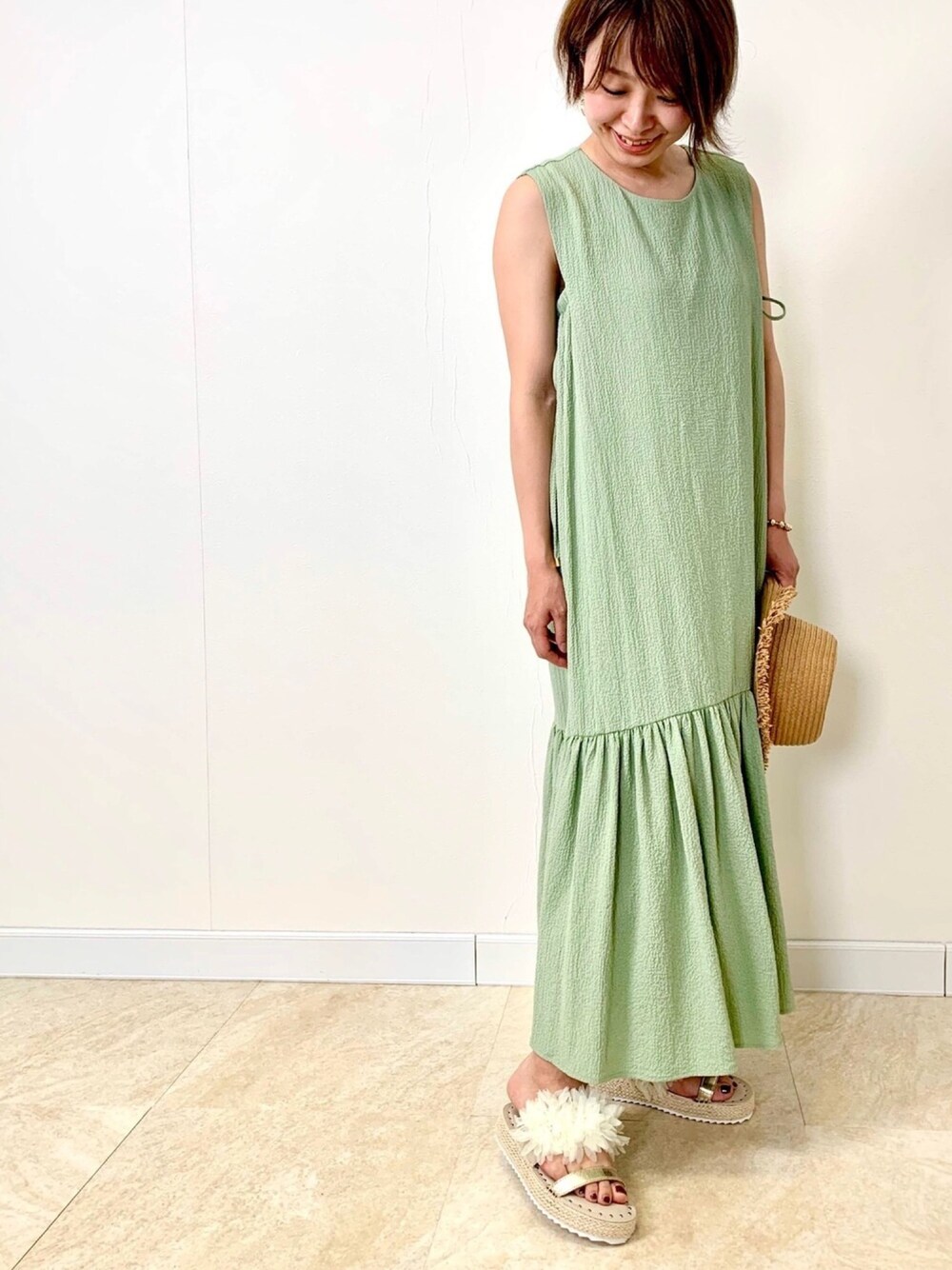 グリーン系のワンピース、ホワイト系のサンダル、ゴールド系のブレスレットを着用したレディースの夏コーディネートの1枚目の写真