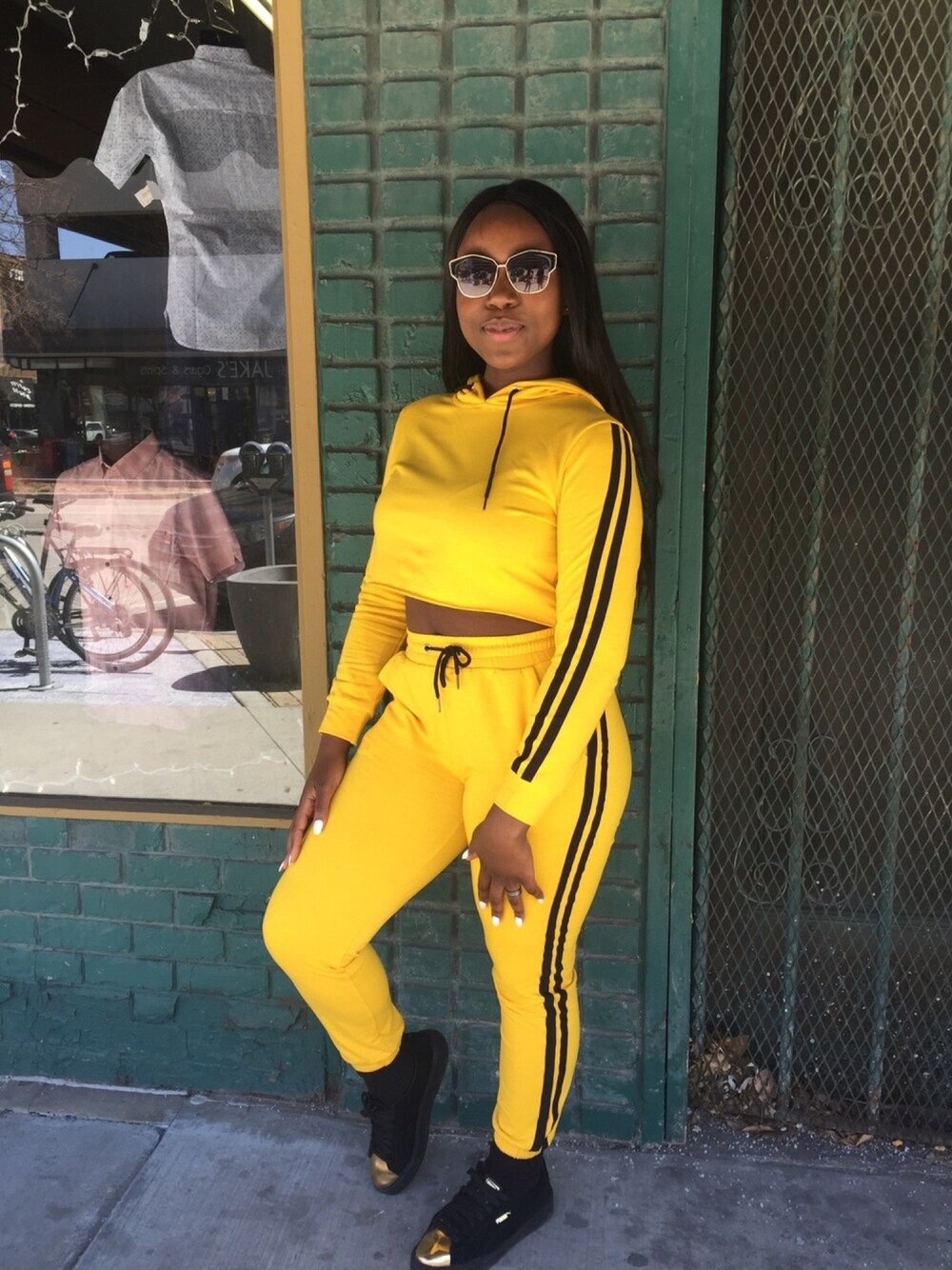 イエロー系のパーカー、イエロー系のその他パンツ、ブラック系のスニーカーを着用したレディースの秋コーディネートの1枚目の写真