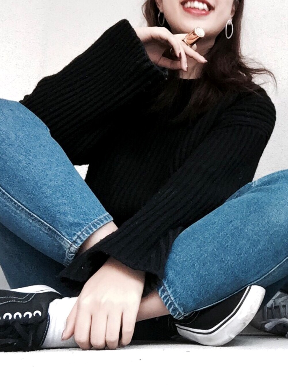 ブラック系のニット/セーター、ブルー系のデニムパンツ、ブラック系のスニーカーを着用したレディースの春コーディネートの1枚目の写真