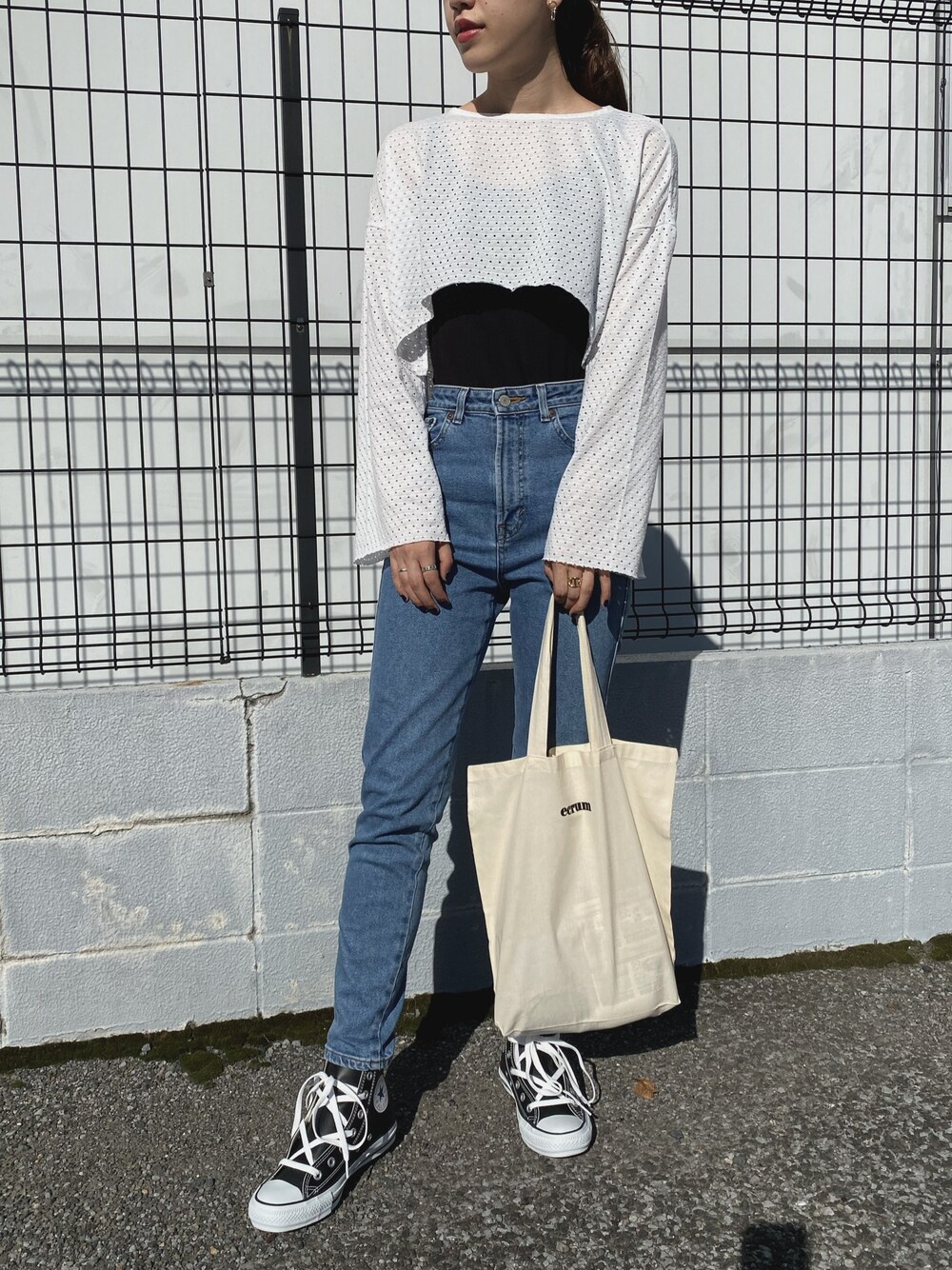 ブルー系のデニムパンツ、ベージュ系のトートバッグ、ブラック系のスニーカーを着用したレディースの秋コーディネートの1枚目の写真