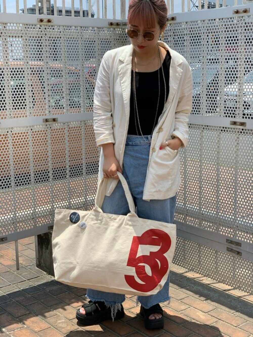 レッド系のトートバッグ、ピンク系のサングラスを着用したレディースの夏コーディネートの1枚目の写真