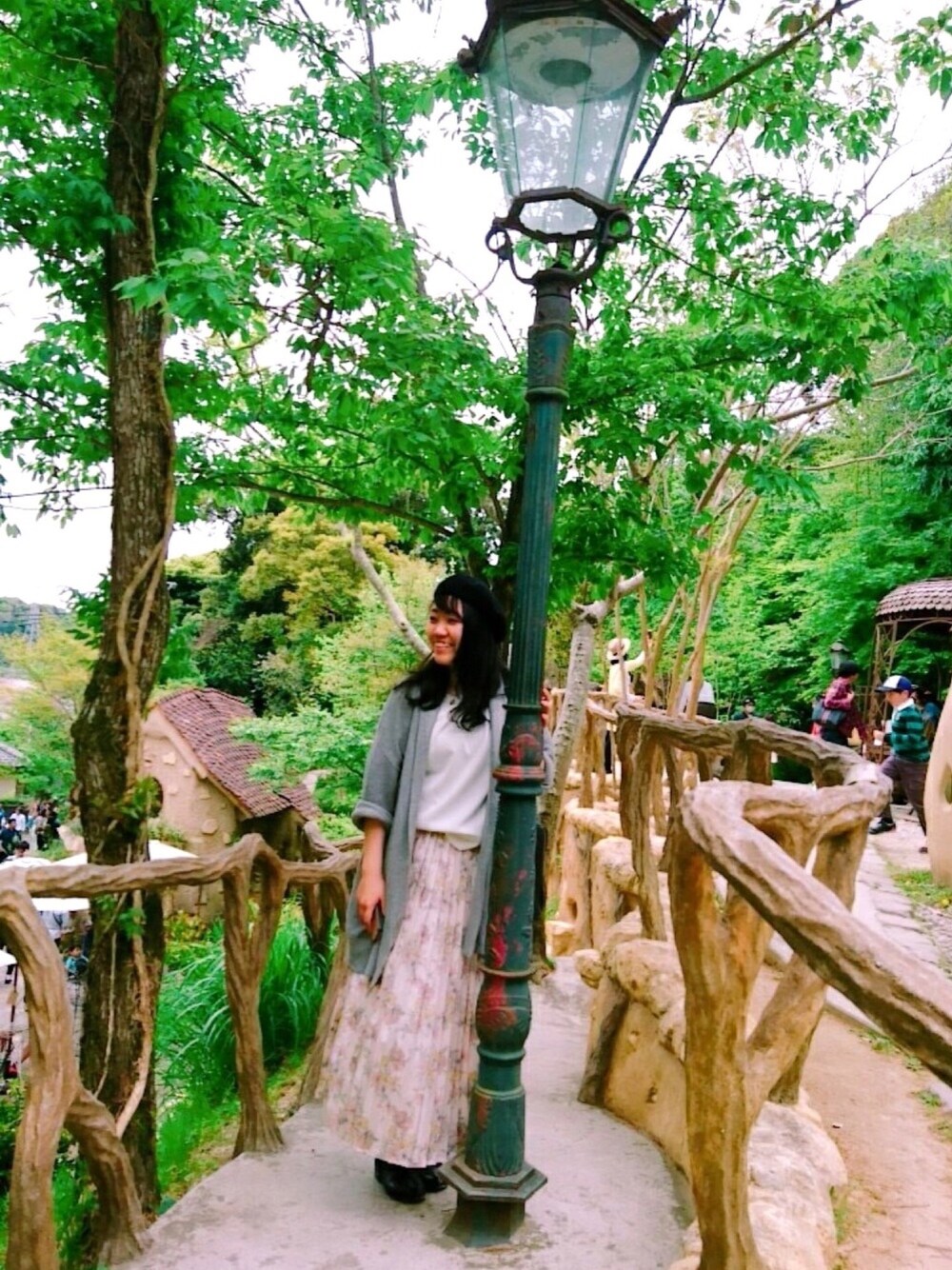 ピンク系のスカート、グレー系のカーディガン/ボレロ、ブラック系のブーツを着用したレディースの春コーディネートの1枚目の写真