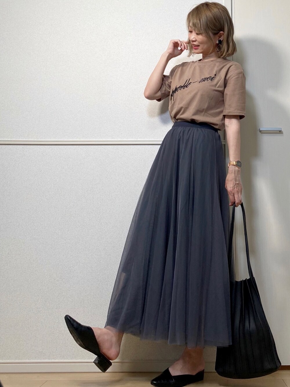 ブラック系のスカート、ブラウン系のTシャツ/カットソー、ブラック系のトートバッグを着用したレディースの夏コーディネートの1枚目の写真