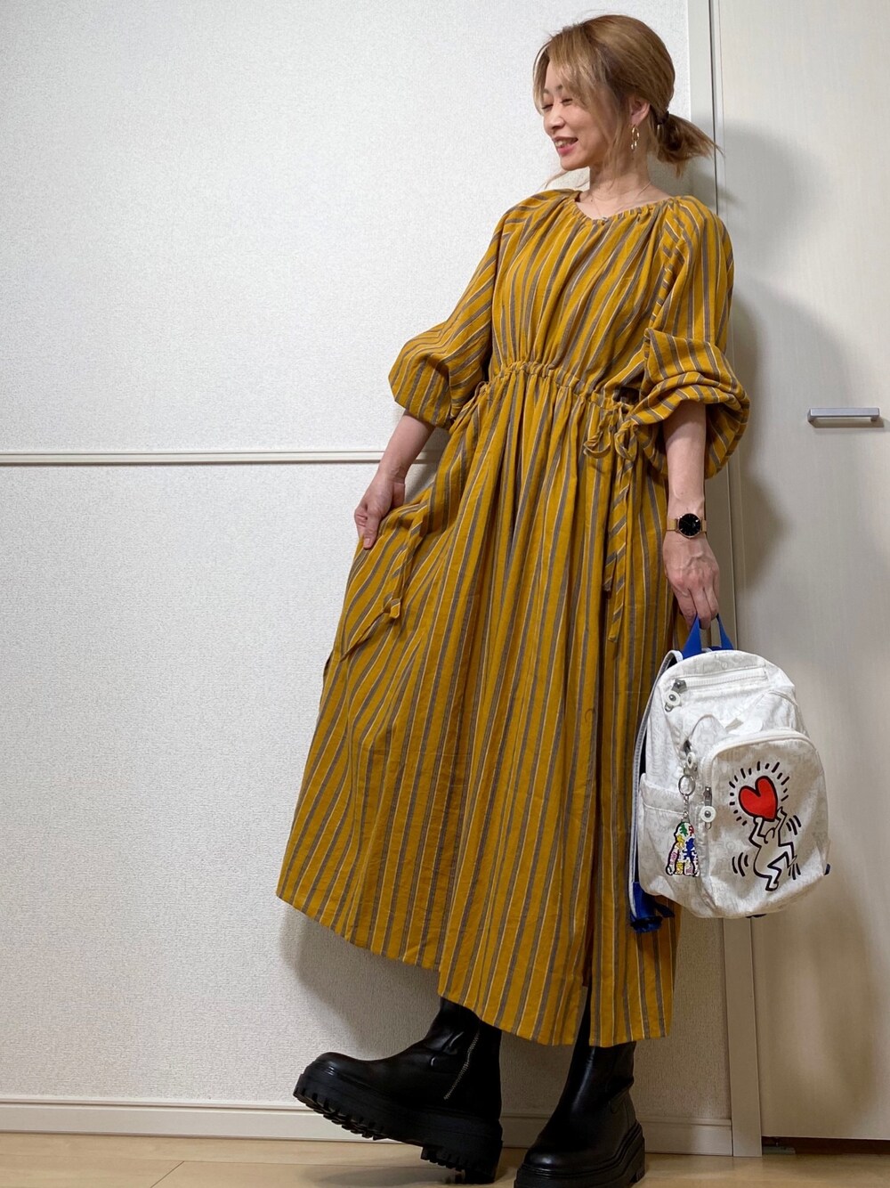 イエロー系のシャツワンピース、その他のバックパック/リュック、ゴールド系のイヤーカフを着用したレディースの秋コーディネートの1枚目の写真