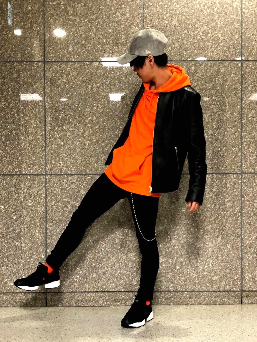 ブラック系のライダースジャケット、ブラック系のその他パンツ、オレンジ系のパーカーを着用したメンズの秋コーディネートの1枚目の写真