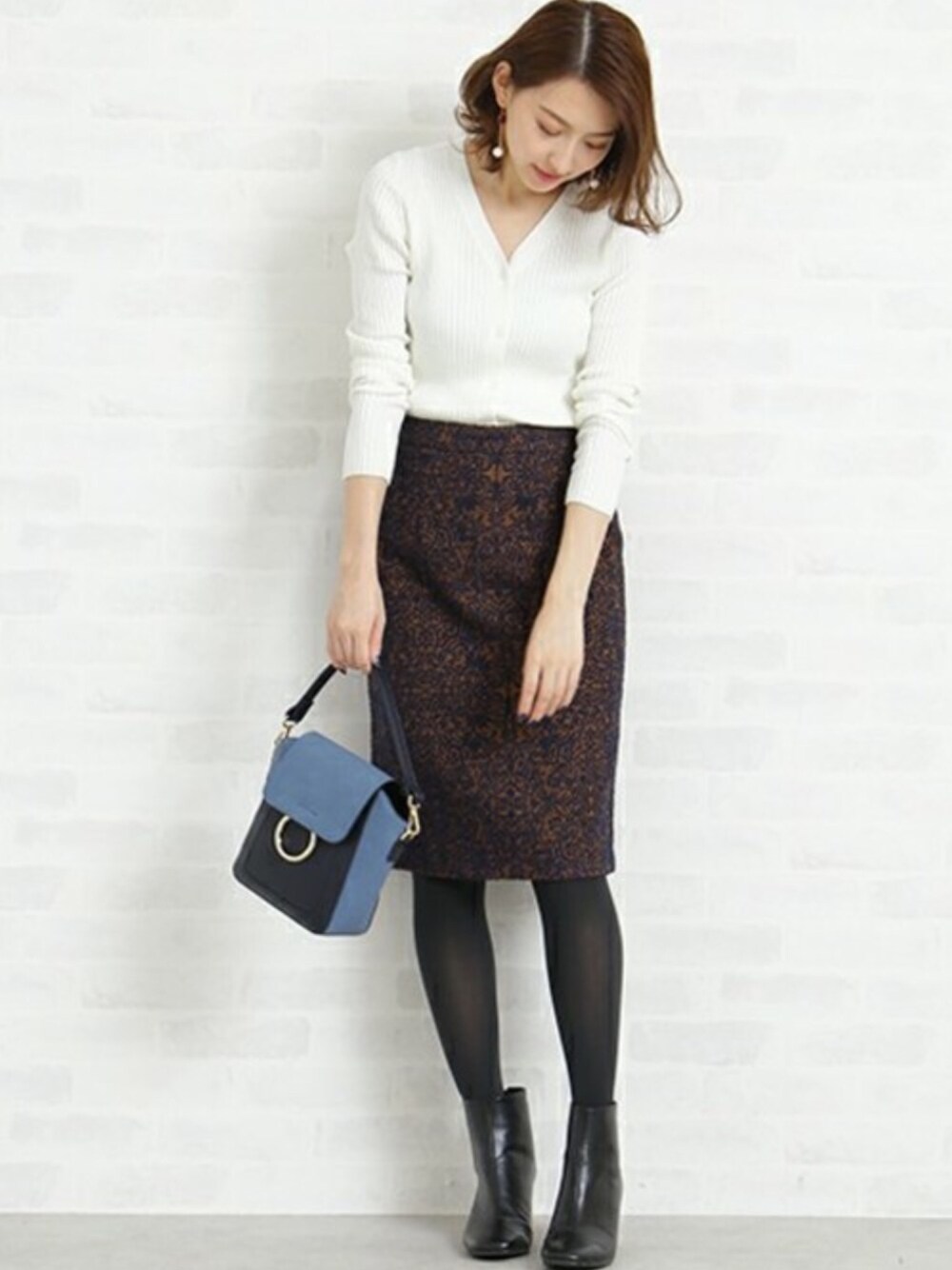 ホワイト系のカーディガン/ボレロ、ブルー系のトートバッグ、ブラック系のブーティを着用したレディースの秋コーディネートの1枚目の写真