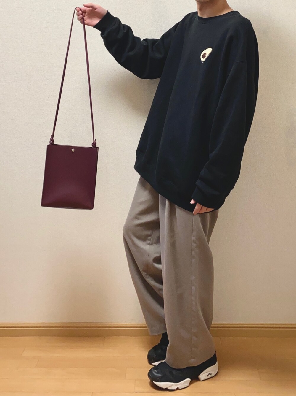 パープル系のショルダーバッグ、ブラック系のTシャツ/カットソー、ベージュ系のスラックスを着用したメンズの春コーディネートの1枚目の写真